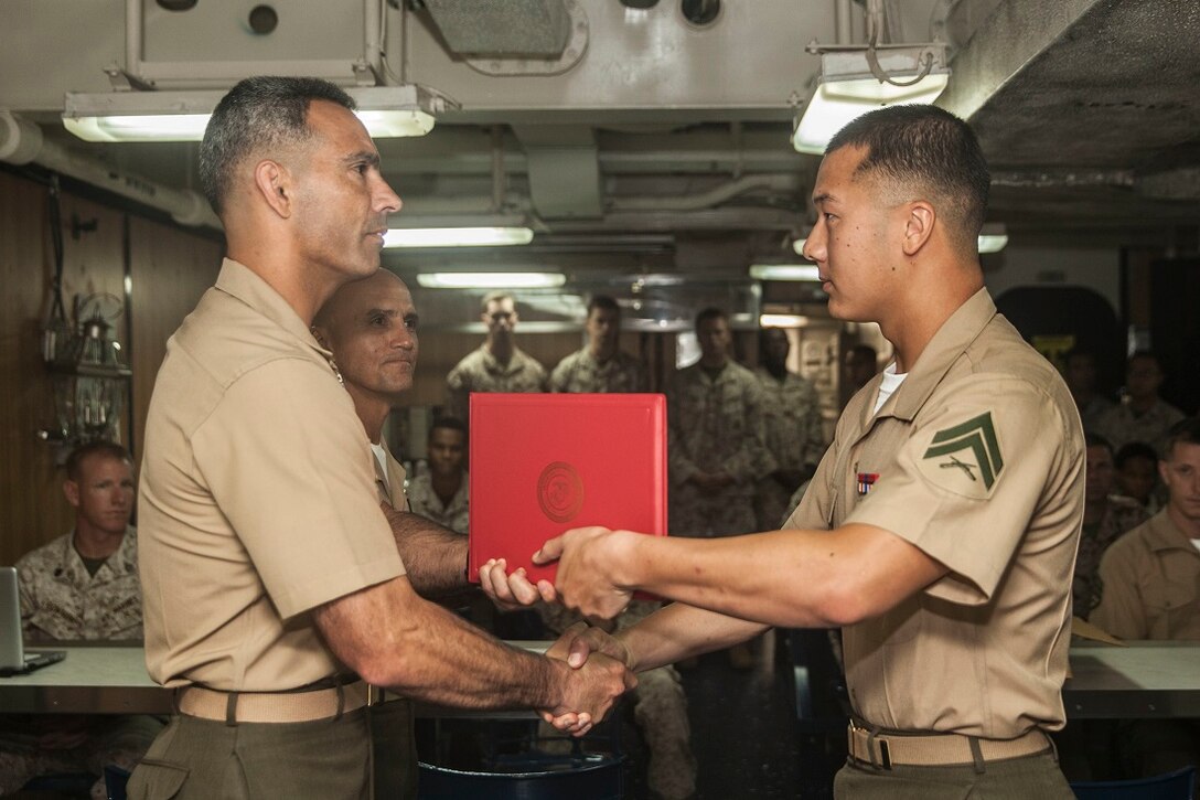 U.S. Marine Lt. Col. Wilfred Rivera, left, presents Cpl. Derek K. Tang with a certificate of commendation during a graduation ceremony for the 15th Marine Expeditionary Unit’s Corporals Course class 3-15 aboard the USS Rushmore (LSD 47). Rivera is the commanding officer of Combat Logistics Battalion 15, 15th MEU and Tang is a team leader with Kilo Company, Battalion Landing Team 3rd Battalion, 1st Marine Regiment, 15th MEU. During corporals course, the Marines learned a variety of things including leadership skills, sword manual, Marine Corps history, and combat conditioning skills. The 15th MEU is embarked on the Essex Amphibious Ready Group and deployed to maintain regional security in the U.S. 5th Fleet area of operations. (U.S. Marine Corps photo by Sgt. Emmanuel Ramos/Released)