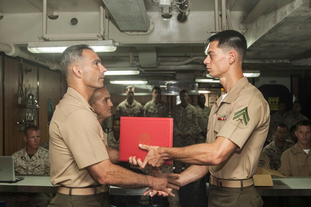 U.S. Marine Lt. Col. Wilfred Rivera, left, presents Cpl. Jeffery S. Salois with a meritorious mast during a graduation ceremony for the 15th Marine Expeditionary Unit’s Corporals Course class 3-15 aboard the USS Rushmore (LSD 47). Rivera is the commanding officer of Combat Logistics Battalion 15, 15th Marine Expeditionary Unit and Salois is a team leader with Kilo Company, Battalion Landing Team 3rd Battalion, 1st Marine Regiment, 15th MEU. During corporals course, the Marines learned a variety of things including leadership skills, sword manual, Marine Corps history, and combat conditioning skills. The 15th MEU is embarked on the Essex Amphibious Ready Group and deployed to maintain regional security in the U.S. 5th Fleet area of operations. (U.S. Marine Corps photo by Sgt. Emmanuel Ramos/Released)