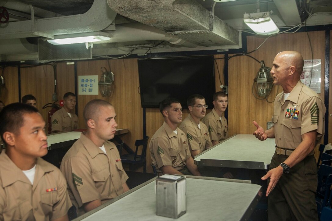 U.S. Marine Sgt. Maj. Carlos M. Murcia, right, speaks to members of the 15th Marine Expeditionary Unit’s Corporals Course class 3-15 during a graduation ceremony aboard the USS Rushmore (LSD 47). Murcia is the sergeant major for Combat Logistics Battalion 15, 15th Marine Expeditionary Unit. He spoke to the Marines about the significance and role noncommissioned officers have on mission accomplishment. During corporals course, the Marines learned a variety of things including leadership skills, sword manual, Marine Corps history, and combat conditioning skills. The 15th MEU is embarked on the Essex Amphibious Ready Group and deployed to maintain regional security in the U.S. 5th Fleet area of operations. (U.S. Marine Corps photo by Sgt. Emmanuel Ramos/Released)