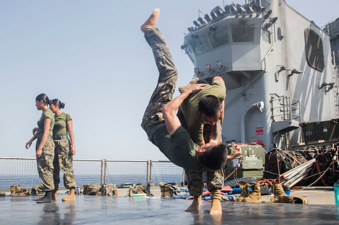U.S. Marine Lance Cpl. Joseph Castro executes an over-the-shoulder throw on Lance Cpl. Hector Mota during a Marine Corps Martial Arts Program course aboard the USS Rushmore (LSD 47). Castro is a motor transportation operator and Mota is an optics technician with Combat Logistics Battalion 15, 15th Marine Expeditionary Unit. MCMAP trains Marines on hand-to-hand combat skills essential to mission readiness, as well as a good source of physical fitness while deployed. The 15th MEU is embarked on the Essex Amphibious Ready Group and deployed to maintain regional security in the U.S. 5th Fleet area of operations. (U.S. Marine Corps photo by Sgt. Emmanuel Ramos/Released)