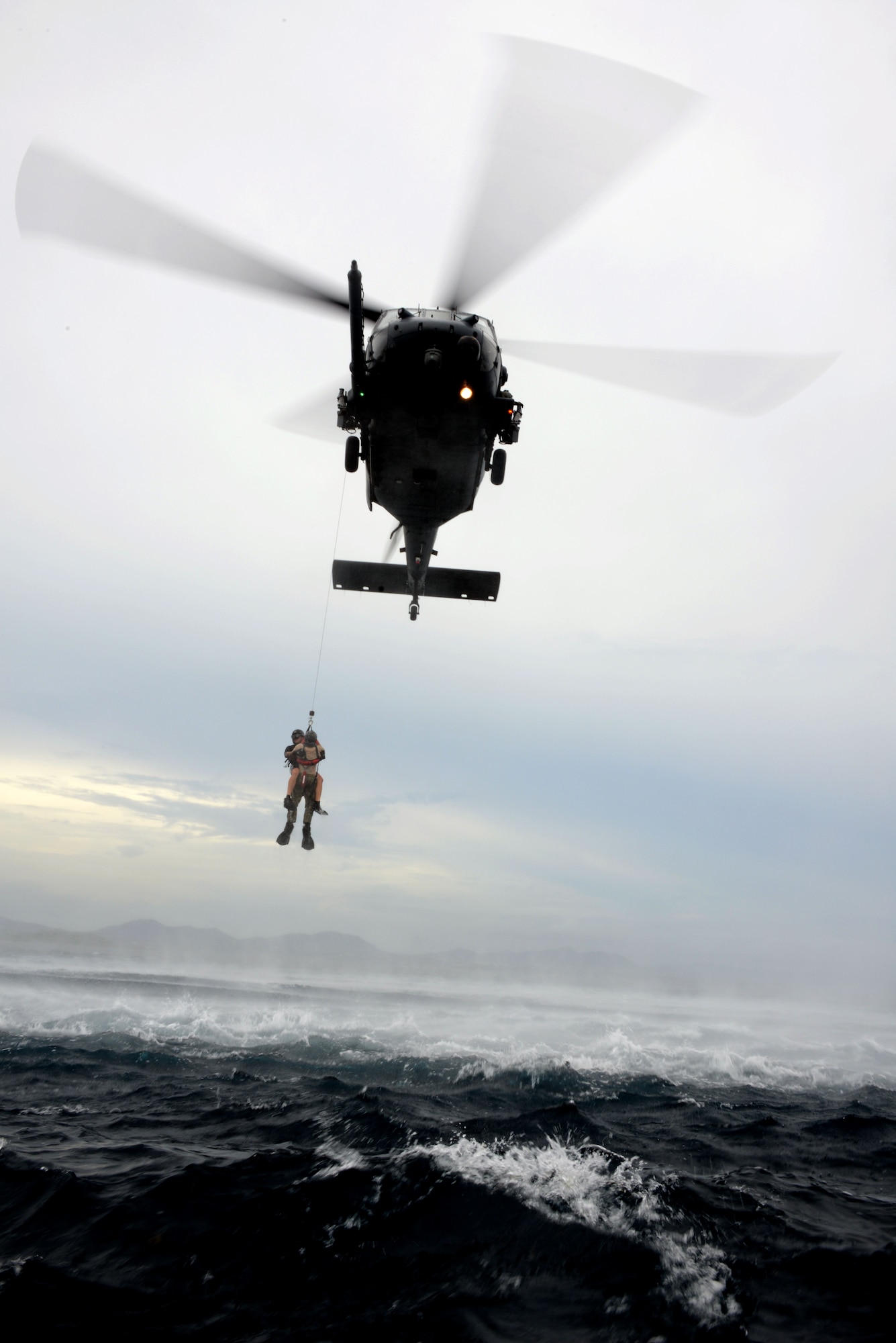 A 320th Special Tactics Squadron pararescueman hoists a Gold Team member out of the water into a Kadena-based HH-60 from the 33rd Rescue Squadron during Gold Thunder 2.0 held at Camp Hansen July 24, 2015.  The exercise scenario ended with a sanitation and evacuation of the forward operating location by water via rotary wing aircraft.  Gold Thunder 2.0 is a humanitarian assistance/disaster relief scenario exercise put together to train the combat mission support personnel in land and water navigation, establishing a special tactics operations center and a forward operating logistics hub along with other skills such as all-terrain vehicle qualification training, Krav Maga training and exfiltration capabilities with rotary wing aircraft. (U.S. Air Force photo by Tech. Sgt. Kristine Dreyer)    