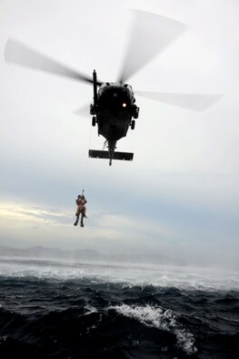 A 320th Special Tactics Squadron pararescueman hoists a Gold Team member out of the water into a Kadena-based HH-60 from the 33rd Rescue Squadron during Gold Thunder 2.0 held at Camp Hansen July 24, 2015.  The exercise scenario ended with a sanitation and evacuation of the forward operating location by water via rotary wing aircraft.  Gold Thunder 2.0 is a humanitarian assistance/disaster relief scenario exercise put together to train the combat mission support personnel in land and water navigation, establishing a special tactics operations center and a forward operating logistics hub along with other skills such as all-terrain vehicle qualification training, Krav Maga training and exfiltration capabilities with rotary wing aircraft. (U.S. Air Force photo by Tech. Sgt. Kristine Dreyer)    