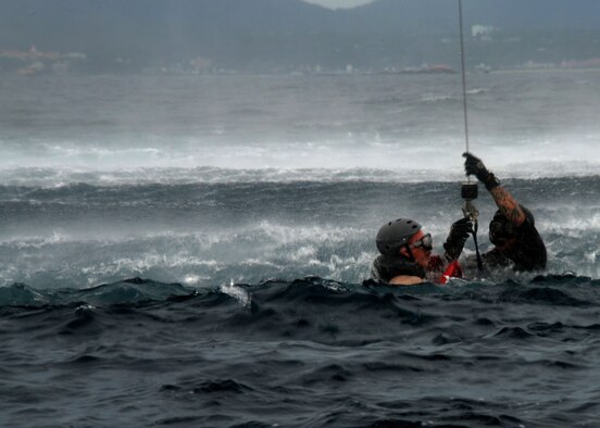 A 320th Special Tactics Squadron pararescueman prepared to hoist a Gold Team member out of the water into a Kadena-based HH-60 from the 33rd Rescue Squadron during Gold Thunder 2.0 held at Camp Hansen July 24, 2015.  The exercise scenario ended with a sanitation and evacuation of the forward operating location by water via rotary wing aircraft.  Gold Thunder 2.0 is a humanitarian assistance disaster/relief scenario exercise put together to train the combat mission support personnel in land and water navigation, establishing a special tactics operations center and a forward operating logistics hub along with other skills such as all-terrain vehicle qualification training, Krav Maga training and exfiltration capabilities with rotary wing aircraft. (U.S. Air Force photo by Tech. Sgt. Kristine Dreyer)    