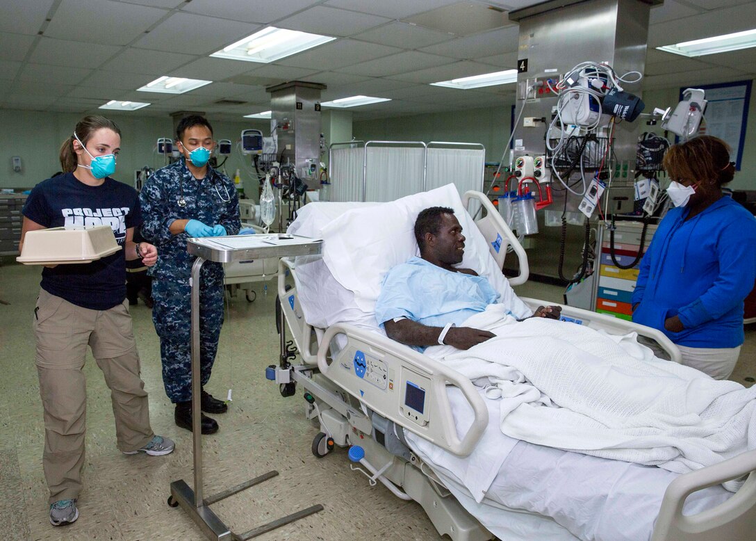 A hospital corpsman and a volunteer with Project Hope look after a patient on the hospital ship USNS Mercy after a patient transport mission in Arawa,  Autonomous Region Of Bougainville, Papua New Guinea, June 30, 2015. At the request of the government of Bougainville, Mercy launched one of its helicopters to transport six passengers, including one infant, who had swam ashore following their ship going down off the coast of Carteret Island in Papua New Guinea. The passengers were transported to Mercy and provided medical assistance. According to Navy doctors, all passengers are in good condition. Mercy is in Papua New Guinea as part of Pacific Partnership 2015. 