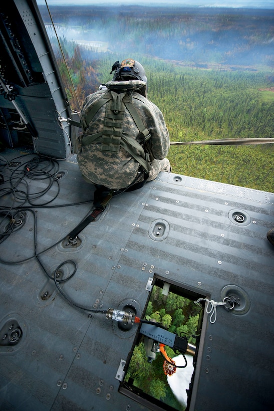 Army Sgt. Philip Peter looks out his UH-60 Black Hawk helicopter while dropping water from a bambi bucket to support firefighting efforts near Tok, Alaska, June 26, 2015. Peter is a crew chief assigned to the Alaska National Guard's 1st Battalion, 207th Aviation Regiment.