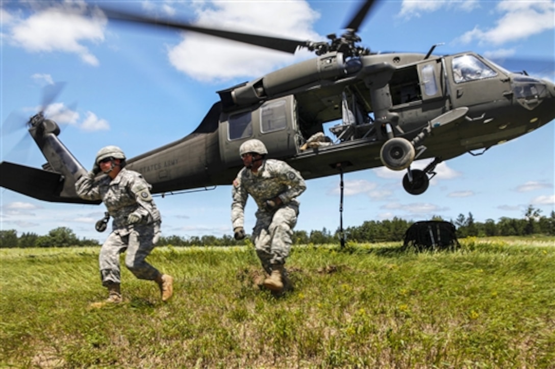 Army Spcs. Crystal Latimer, left, and Isaac Ravelo move away from a UH-60 Black Hawk helicopter after attaching a slingload containing medical cargo during Global Medic on Fort McCoy, Wis., June 16, 2015. Latimer and Ravelo are assigned to the Army Reserve's 317th Military Police Battalion and the helicopter crew is assigned to the Army Reserve's Company F, 1st Battalion, 214th Aviation Regiment.