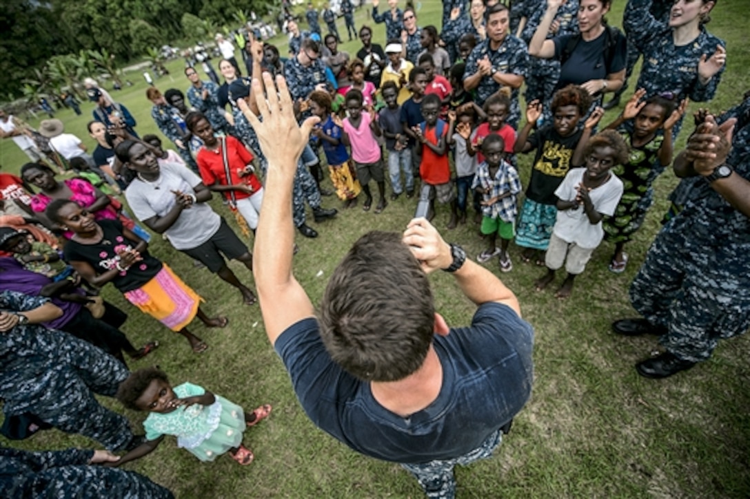 U.S. Navy Petty Officer Class Steve Lamonica interacts with a crowd while performing during Pacific Partnership 2015 in Arawa, Papua New Guinea, June 28, 2015. Lamonica is a musician attached to the hospital ship USNS Mercy.