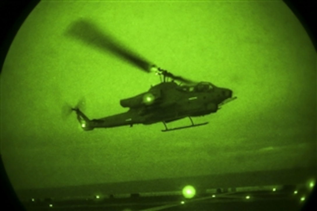As seen through a night-vision device, a U.S. Marine Corps AH-1 Super Cobra flies off the flightline aboard the USS Kearsarge during an exercise at sea, June 25, 2015. The helicopter is assigned to Marine Medium Tiltrotor Squadron 162, 26th Marine Expeditionary Unit.