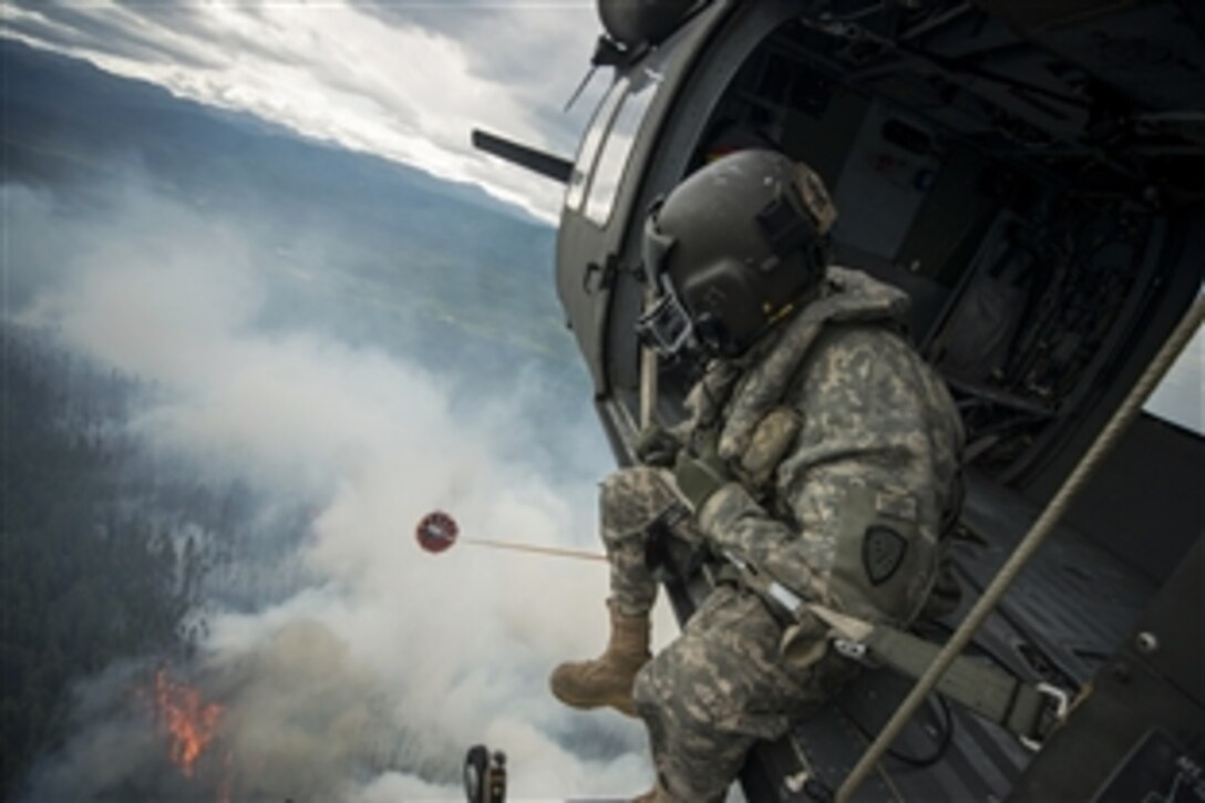 Army Sgt. Philip Peter looks out from a UH-60 Black Hawk helicopter while dropping water from a bambi bucket to support firefighting efforts near Tok, Alaska, June 26, 2015. Peter is a crew chief assigned to the Alaska National Guard's 1st Battalion, 207th Aviation Regiment. 