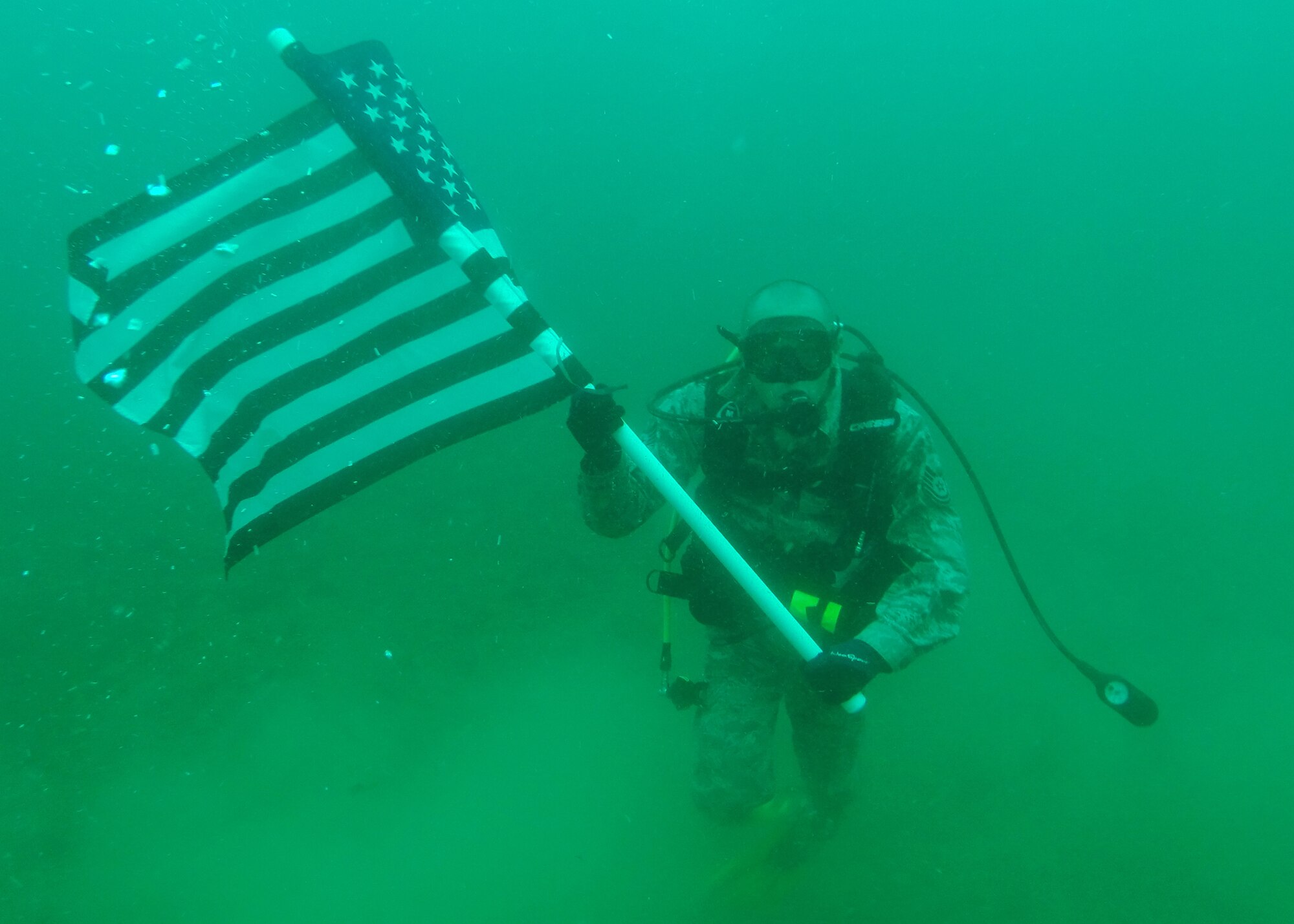 Technical Sgt. Robert Barnes, 325th Communications Squadron quality assurance NCO in charge, holds the U.S. Flag under the ocean water June 26. Barnes had a re-enlistment ceremony 70 feet under water. (U.S. Air Force photo by Airman 1st Class Sergio A. Gamboa/Released) 