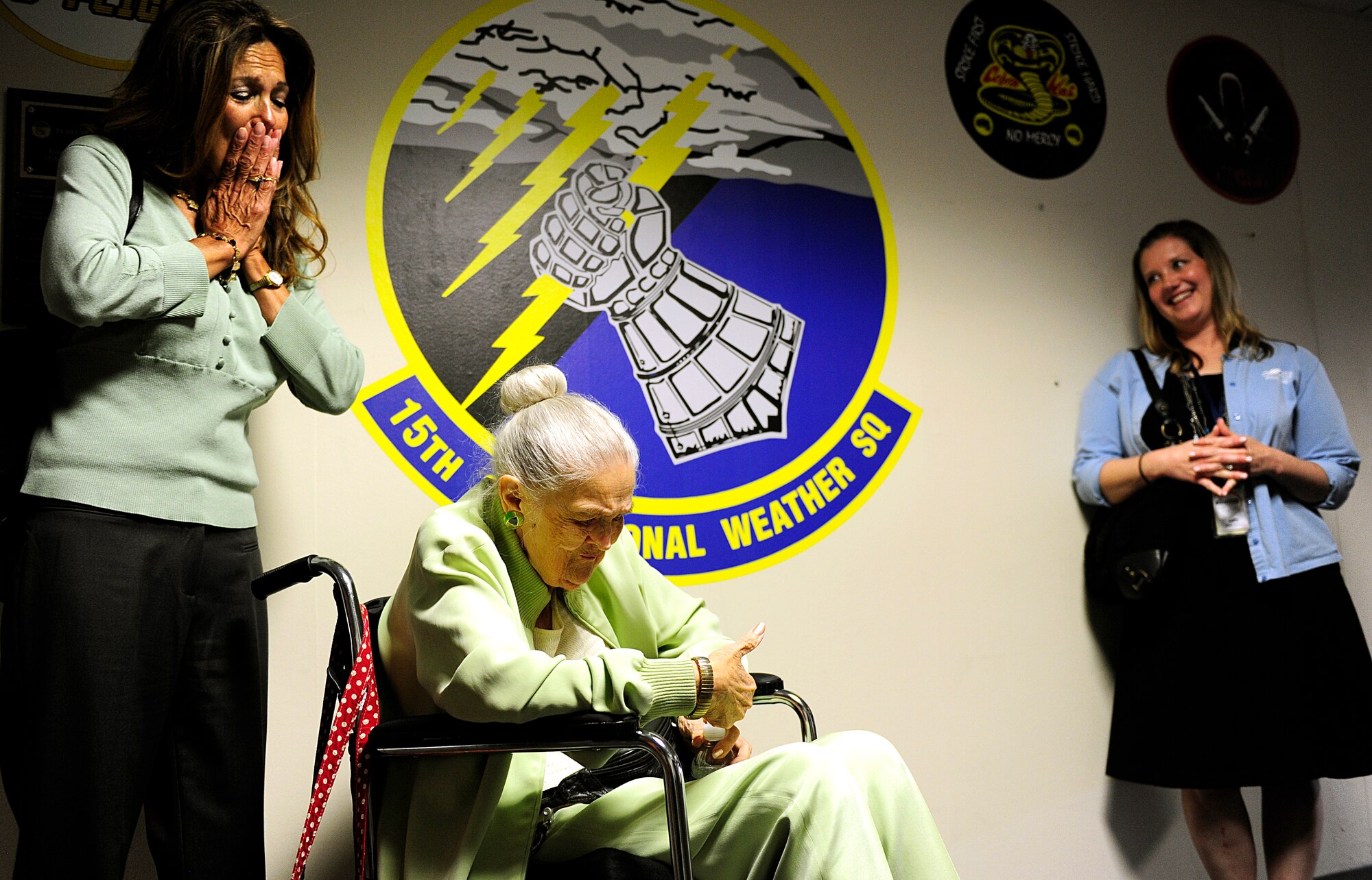 Norma Cadena admires a squadron coin she received from Lt. Col. Danielle Budzko, 15th Operational Weather Squadron commander, during her visit to the squadron at Scott Air Force Base, Ill., June 26, 2015. After she received the coin she kept asking members if they wanted to see it, but wouldn’t let anyone hold it. (U.S. Air Force photo/Staff Sgt. Stephenie Wade) 