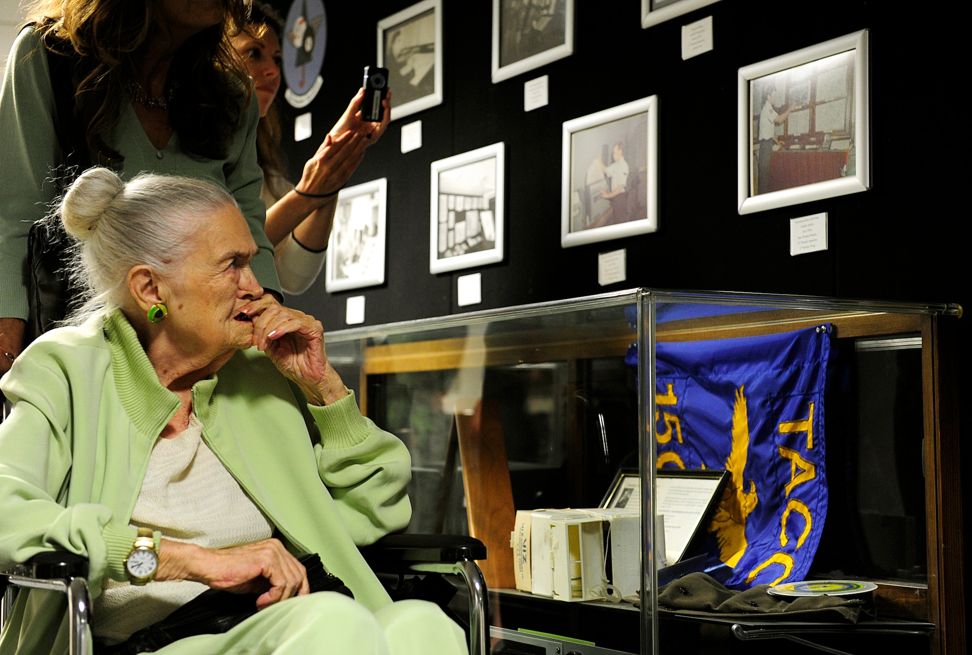 Norma Cadena, 87, views historical photographs and equipment of military weather observers throughout the years at the 15th Operational Weather Squadron, Scott Air Force Base, Ill., June 26, 2015. Cadena was a weather observer during the end of World War II and her last wish was to relive her days as a weather observer. The 15OWS plans to make widen their historical section in the near future. (U.S. Air Force photo/Staff Sgt. Stephenie Wade)
