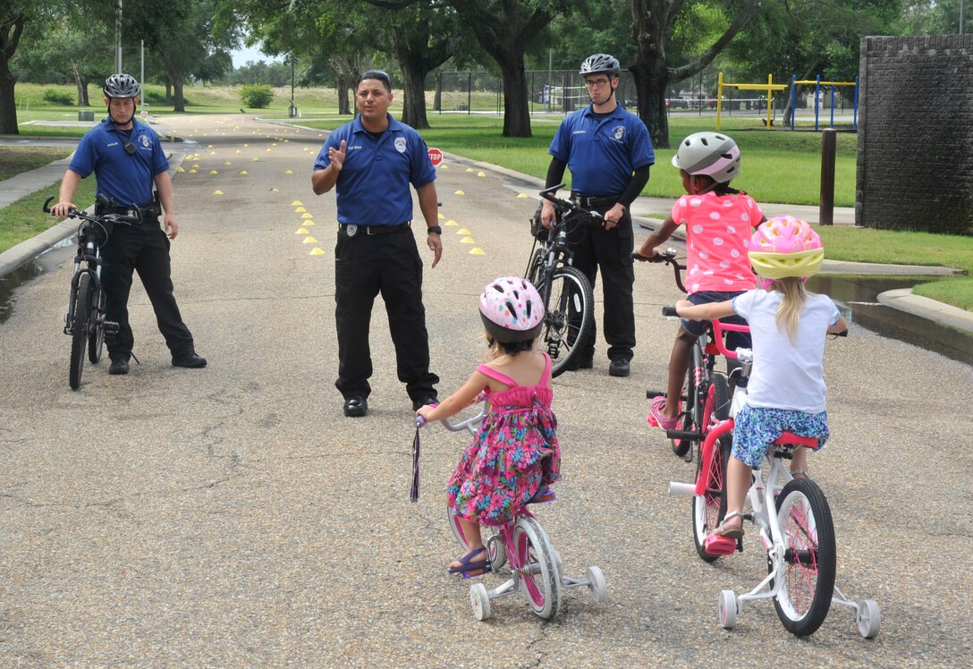 Corporal Juan Diaz, 325th Security Forces Squadron community police officer, teaches children about bike riding safety June 27 at the Belfour Beatty Community Center. The Community Police host the bicycle rodeo every year to improve relations between Tyndall families and security forces and to ensure all children know proper bike riding safety precautions. (U.S. Air Force photo by Airman 1st Class Cody R. Miller/Released)    
