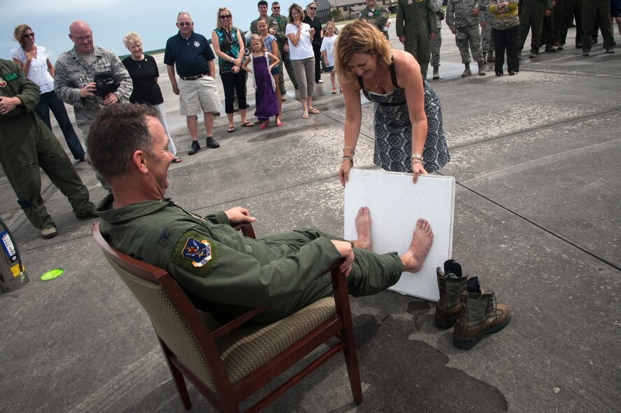 U.S. Air Force Col. Chad Franks, 23d Wing commander, presses his feet against a ceiling tile while his wife Kim holds it in place June 26, 2015, at Moody Air Force Base, Ga. It is a tradition to ‘capture’ a pilot after his final flight and paint his feet green to stamp on a ceiling tile. (U.S. Air Force photo by Andrea Jenkins/Released)
