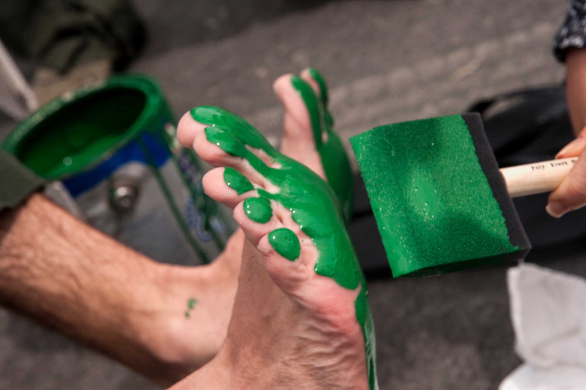 Kim Franks, wife of U.S. Air Force Col. Chad Franks, 23d Wing commander, paints his feet June 26, 2015, at Moody Air Force Base, Ga. The green feet symbol began in Vietnam, when the HH-3E helicopter would land and leave huge impressions resembling giant green footprints. (U.S. Air Force photo by Andrea Jenkins/Released)
