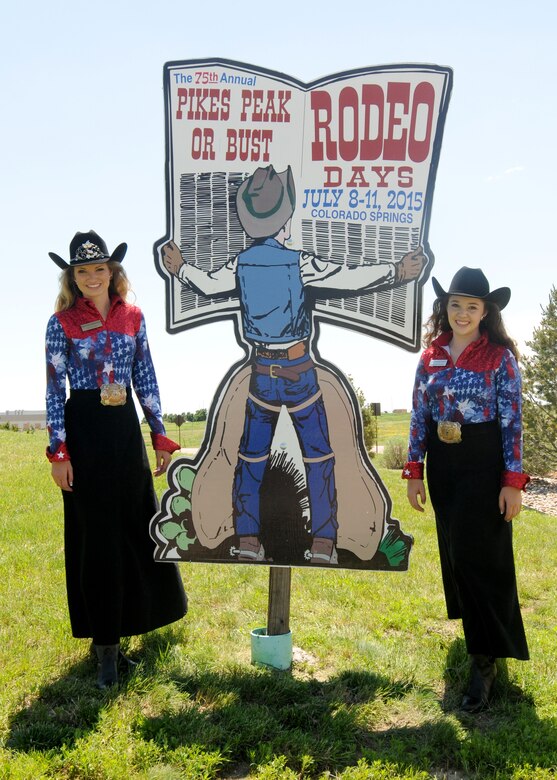 Rachael Braaten, 2015 Girl of the West, 9left) and Allison Mitchell, 2015 Aide to the Girl of the West, pose next to the Pikes peak or Bust Rodeo advertisement Monday, June 29,2015 at Schriever Air Force Base, Colorado. This year marks the 75th anniversary for the Pikes Peak or Bust Rodeo which will take place July 8-11. (U.S. Air Force photo/ Staff Sgt. Debbie Lockhart)