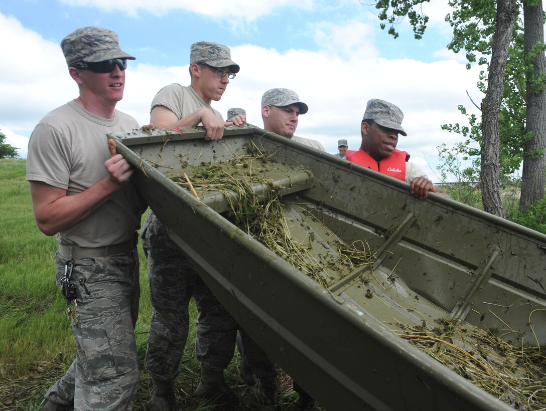 A group of Airmen from the 28th Civil Engineer Squadron empty a boat used to collect weeds out of Gateway Lake at Ellsworth Air Force Base, S.D., June 24, 2015. Clearing the weeds will help sustain the lake environment, protecting animals and other plants that live in the area. (U.S. Air Force Airman Sadie Colbert/Released)