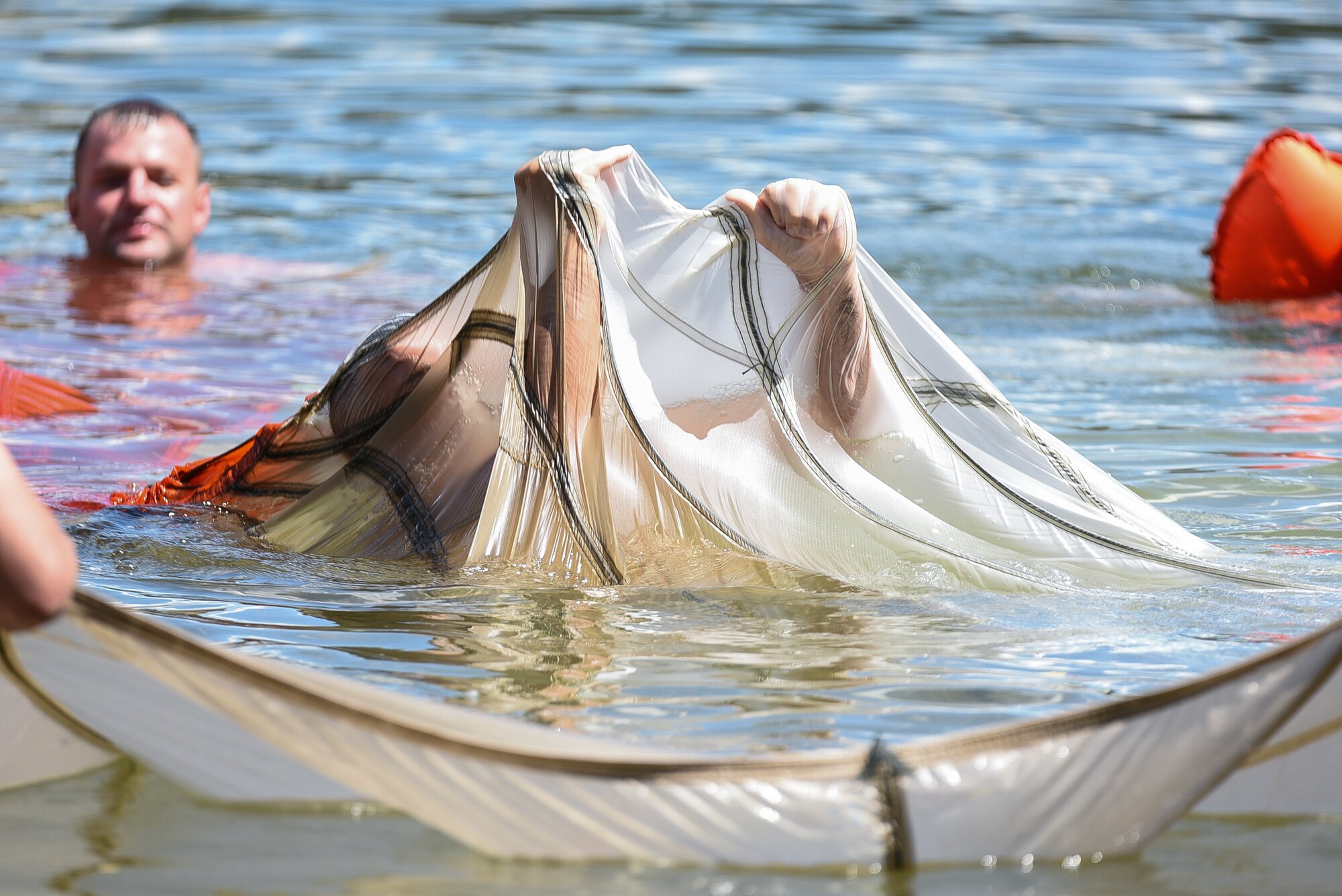 U.S. Air Force Airmen assigned to the 153rd Airlift Wing, Wyoming Air National Guard practice maneuvering out from under a downed canopy during water survival training June 26, 2015, at Camp Guernsey Joint Training Center in Guernsey, Wyo. Aircrew members performed physical training, weapons qualification, water survival, combat survival, and Joint Precision Airdrop Delivery System training during four days of annual training at Guernsey. (U.S. Air National Guard photo by Master Sgt. Charles Delano)