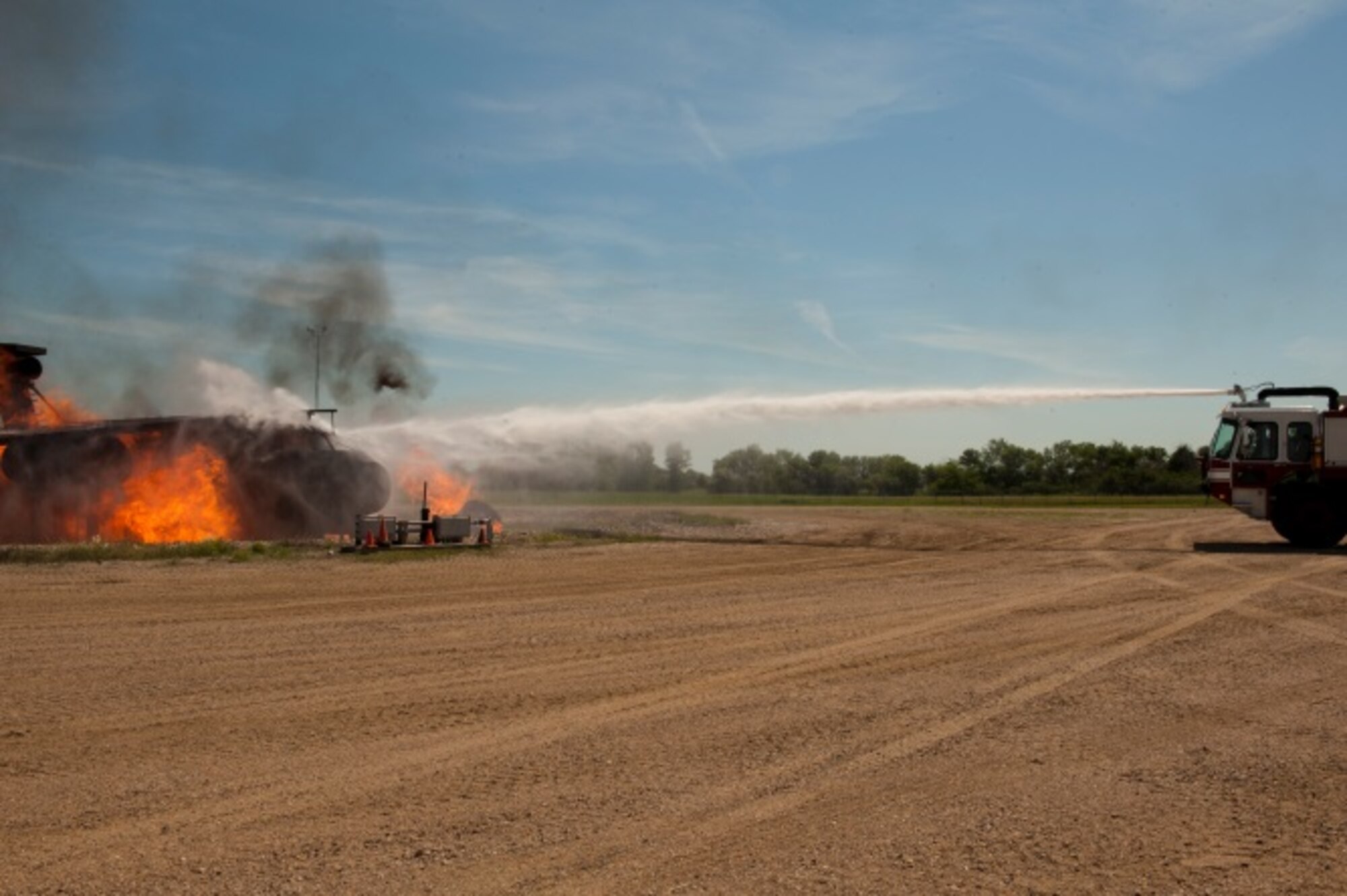 Airmen from the 5th Civil Engineer Squadron put out a live fire during an exercise at Minot Air Force Base, N.D., June 26, 2015. The 5th CES performed the exercise for retired Minot firefighters who held a reunion at the CE fire station. (U.S. Air Force photo/Airman 1st Class Christian Sullivan)