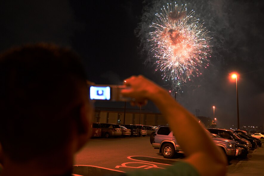A spectator takes pictures of fireworks during the 18th Force Support Squadron’s Rockin’ the Block on Kadena Air Base, Japan, June 27, 2015. Fireworks could be seen from across the installation. Rockin’ the Block was held  as community celebration of the Fourth of July. (U.S. Air Force photo by Senior Airman Omari Bernard)
