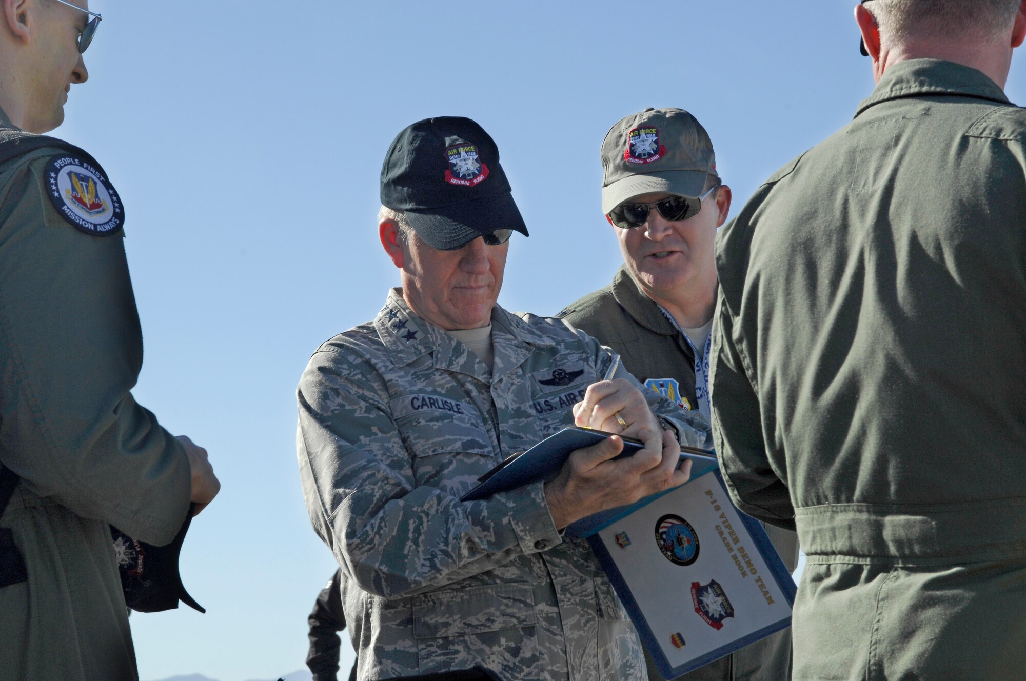U.S. Air Force General Hawk Carlisle, Commander of Air Combat Command, signs the gradebook on the flight line during the Heritage Flight Training Conference at Davis-Monthan Air Force Base, Ariz., Feb, 27, 2015. The paperwork certifies the F-16 pilot as the Viper Demonstration Team pilot. (U.S. Air Force photo by Airmen 1st Class Cheyenne Morigeau/Released)