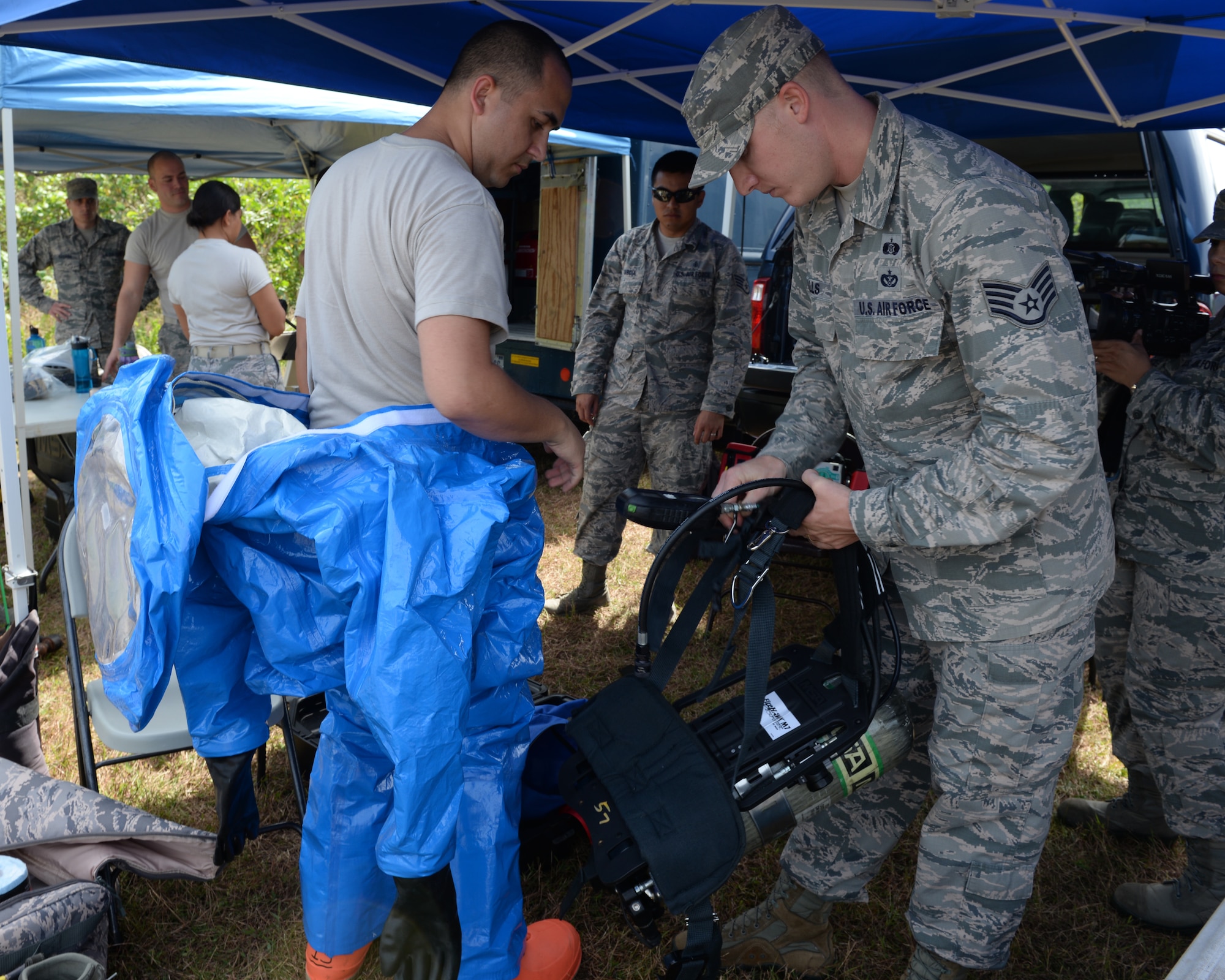 Staff Sgt. Adam Hills, 36th Civil Engineer Squadron, Emergency Management Flight, helps a member of the bioenvironmental team put on gear before performing an exercise during the Philippine Delegation visit Feb. 27, 2015, at Andersen Air Force Base, Guam.  Teams from the Explosive Ordinance Disposal flight, fire prevention and response, emergency management and medical all participated in the exercise that was hosted by the 36th CES for members of the Armed Forces of the Philippines. (U.S. Air Force photo by Senior Airman Cierra Presentado/Released)