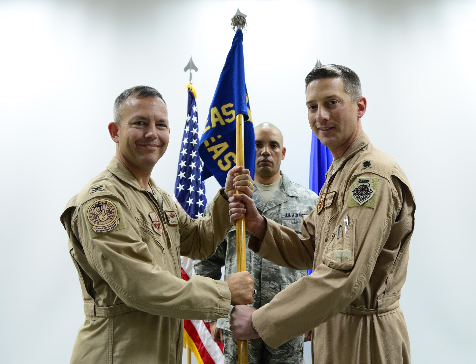 U.S. Air Force Lt. Col. Jeremy Schaad, right, passes the 746th Expeditionary Airlift Squadron guidon to Col. Jim Dittus, 379th Expeditionary Operations Group commander, to officially relinquish command during a change of command ceremony, March 1, 2015, at Al Udeid Air Base, Qatar. Schaad relinquished command of the 746th EAS to Lt. Col. Byron Newell. (U.S. Air Force photo by Senior Airman Kia Atkins)