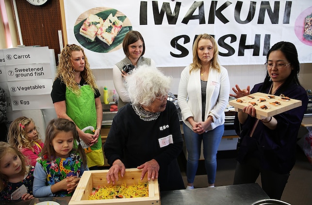 Mikie Watanabe, a cultural adaption specialist aboard Marine Corps Air Station Iwakuni, Japan, helps Kikuko Shinjo, a teacher with Yusu No Sato, a cultural outreach group based in Iwakuni City, instruct station residents on how to properly make Iwakuni sushi, Feb. 27, 2015. Guests celebrated the Japanese Doll Festival “Hinamatsuri,” with Yusu No Sato by helping display “hina-ningyo,” a seven-tiered stand presenting the special dolls of Hinamatsuri that celebrates young girl’s growth and happiness, dressing in traditional Japanese kimonos, and making Iwakuni sushi.