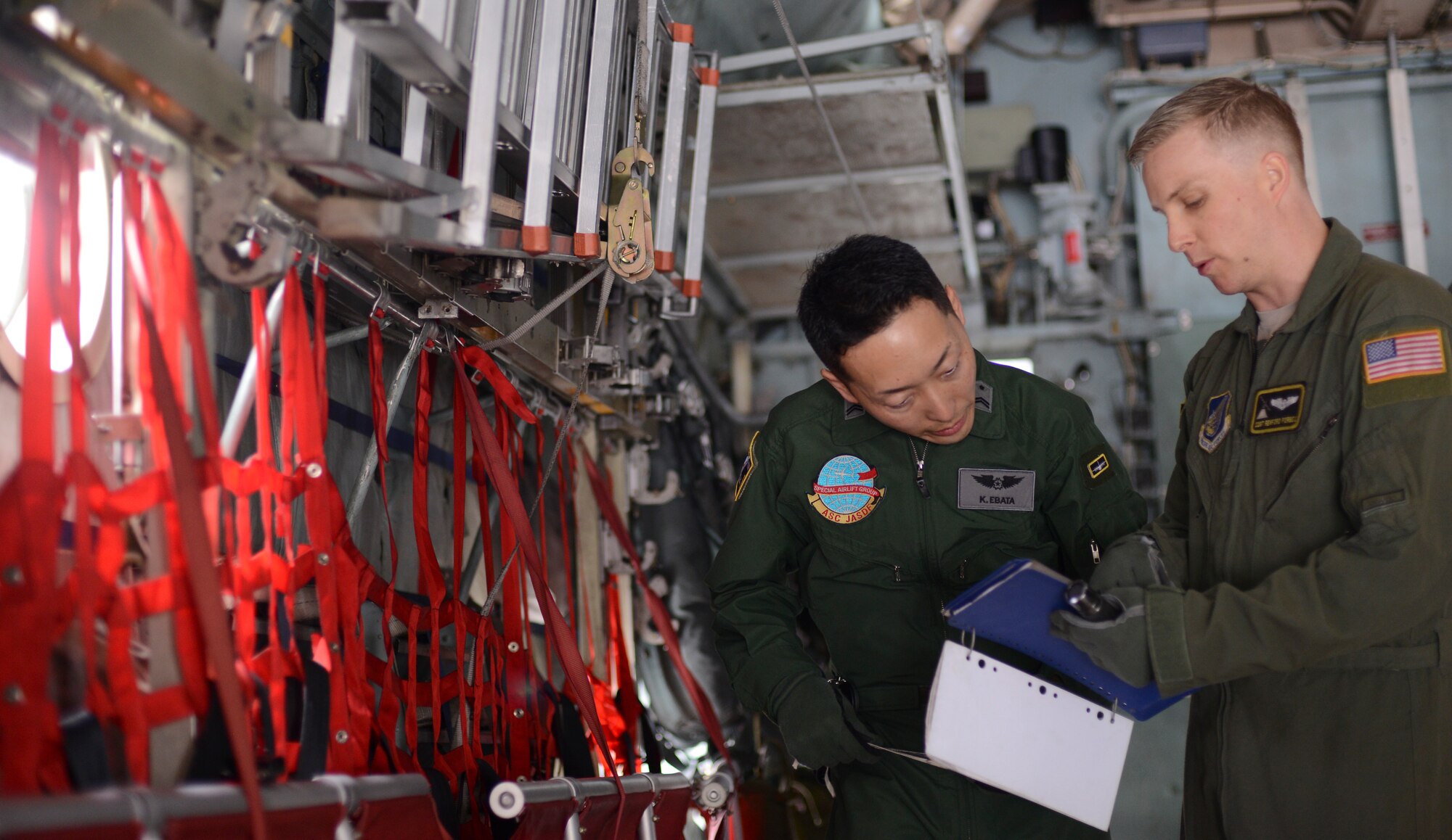 Japan Air Self-Defense Force Tech. Sgt. Kazuyuki Ebata, Special Airlift Wing loadmaster, and Air Force Staff Sgt. Ren Forbes, 36th Airlift Squadron loadmaster, review a preflight checklist before a C-130 flight during the noncommissioned officer exchange program at Yokota Air Base, Japan, Feb. 25, 2015. For the 10-day long program, Ebata shadowed Forbes to see how Yokota’s mission differs from the JASDF’s. (U.S. Air Force photo by Senior Airman Michael Washburn/Released)