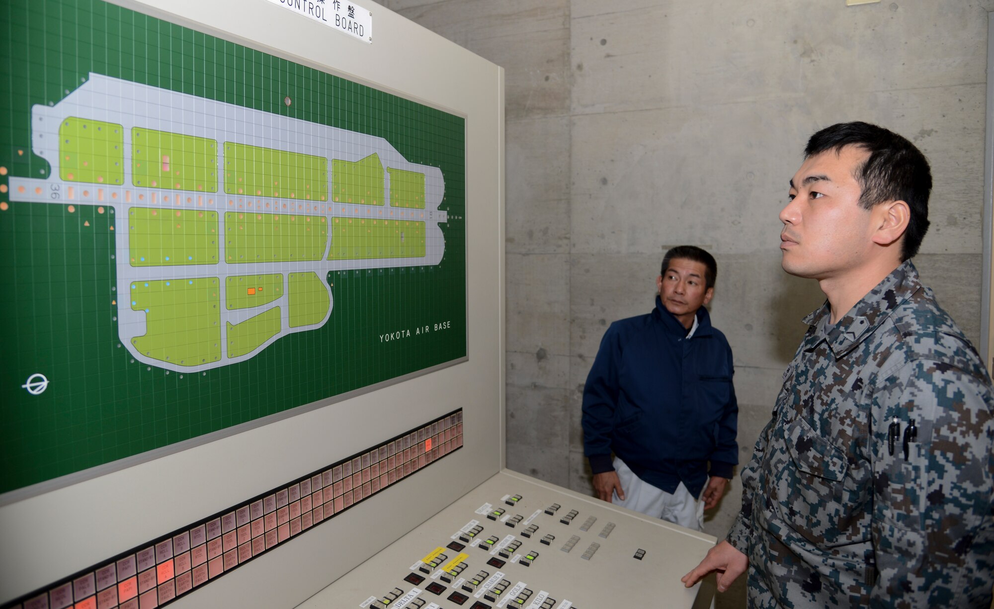 Japan Air-Self Defense Force Staff Sgt. Shinya Kobayashi, 1st Missile Group electrician, looks at the airfield lighting control board during the noncommissioned officer exchange program at Yokota Air Base, Japan, Feb. 20, 2015. From the control board, all lights on the flightline can be lit up so electricians working on the runway can see which lights need to be fixed. (U.S. Air Force photo by Senior Airman Michael Washburn/Released)