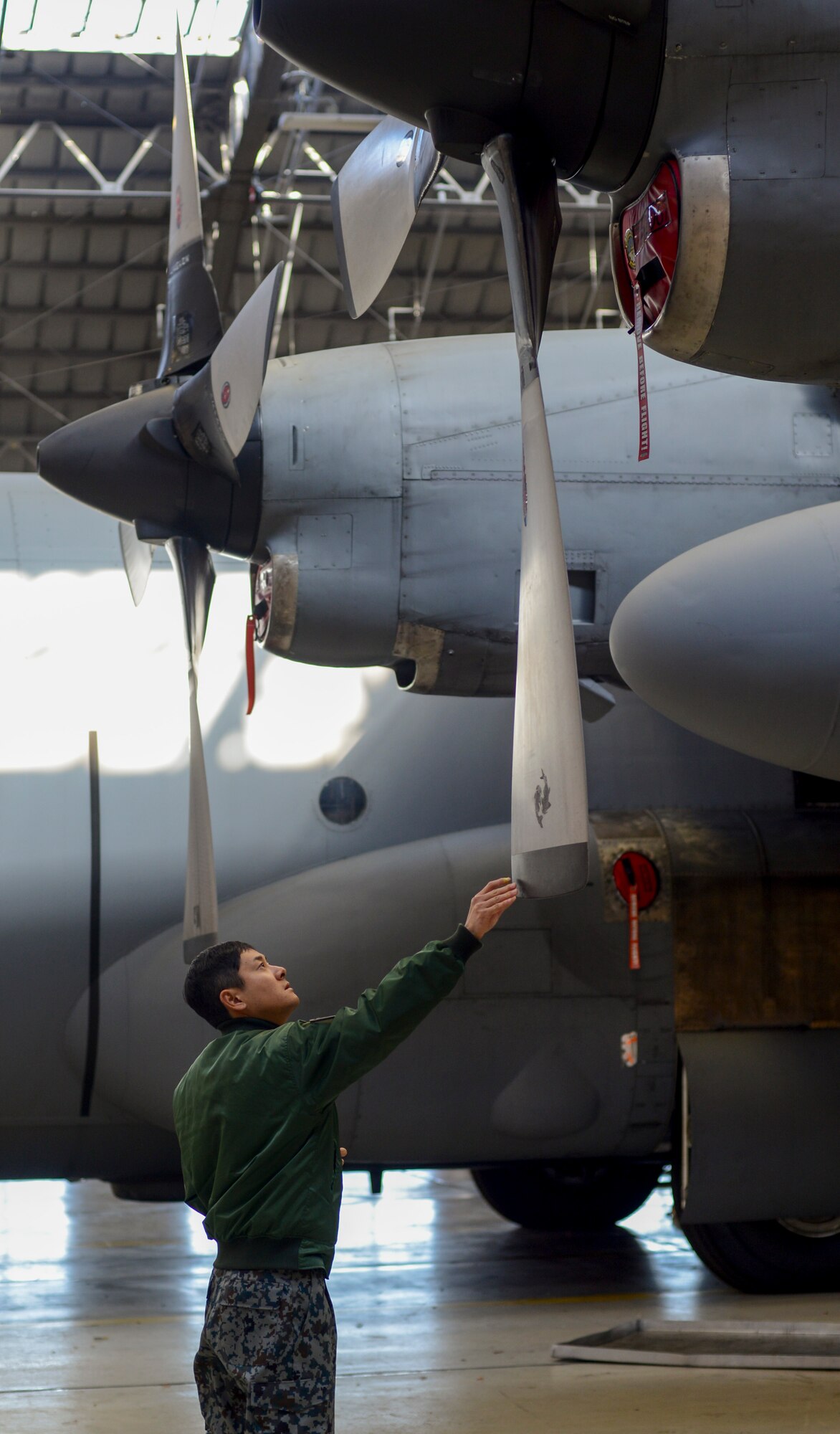 Japan Air-Self Defense Force Staff Sgt. Masahiro Yamamoto, 1st Air Wing flightline maintainer, touches a blade of a C-130 Hercules propeller during the noncommissioned officer exchange program at Yokota Air Base, Japan, Feb. 18, 2015. The 10-day program pairs JASDF members from multiple bases around Japan with U.S. personnel to get a better understanding of the various missions at Yokota and experience a different culture. (U.S. Air Force photo by Senior Airman Michael Washburn/Released)