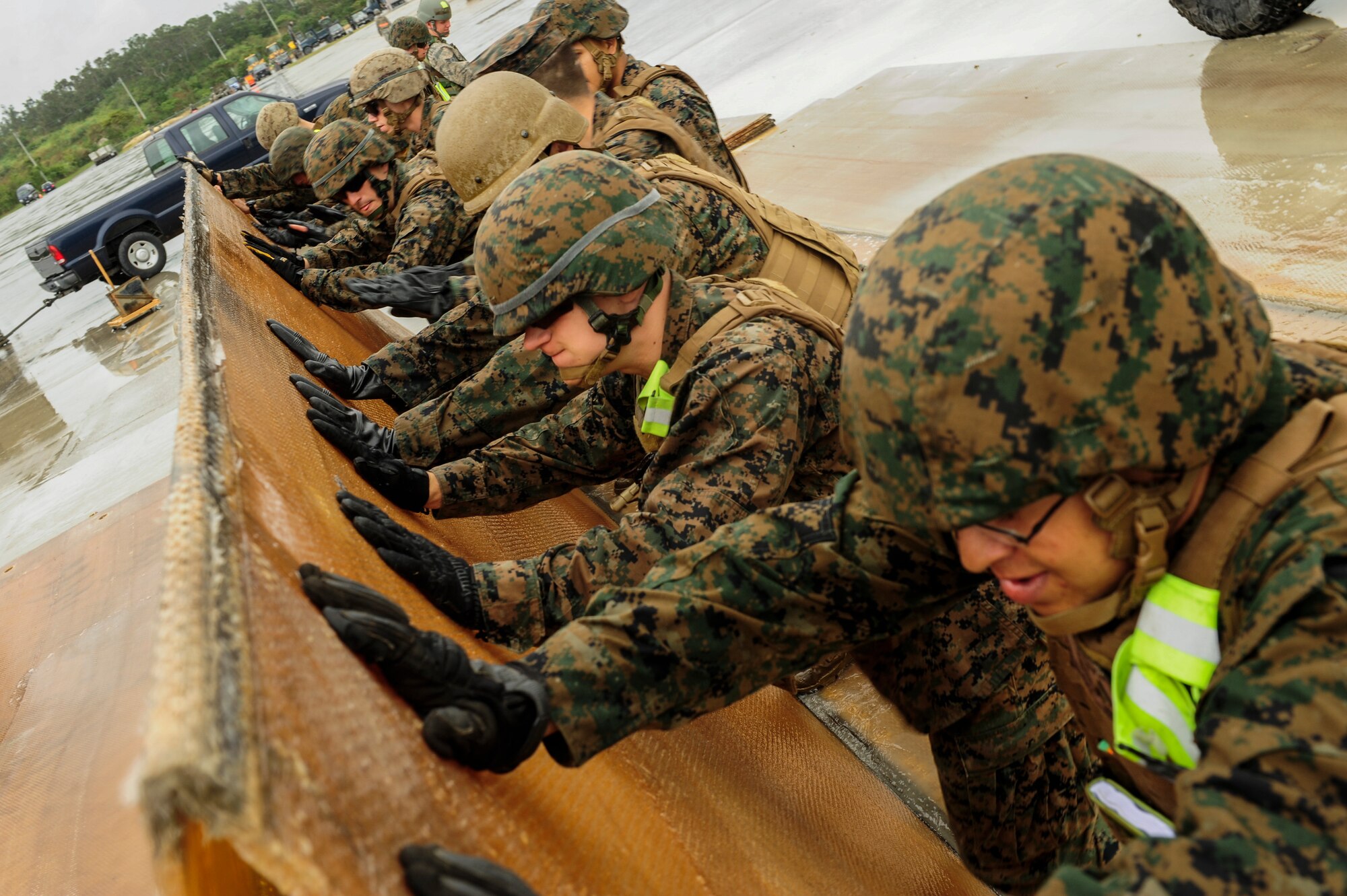 Marines from the 172nd and 171st Engineering Company brace a folded fiberglass mat as it is folded by a forklift at Kadena Air Base, Japan Feb. 26, 2015. The mat is used to repair a damaged runway. Marines from the 172nd and 171st Engineering Companies joined Airmen from the 18th Civil Engineer Squadron in a joint airfield damage and repair contingency exercise for the first time. (U.S. Air Force photo by Airman 1st Class John Linzmeier)