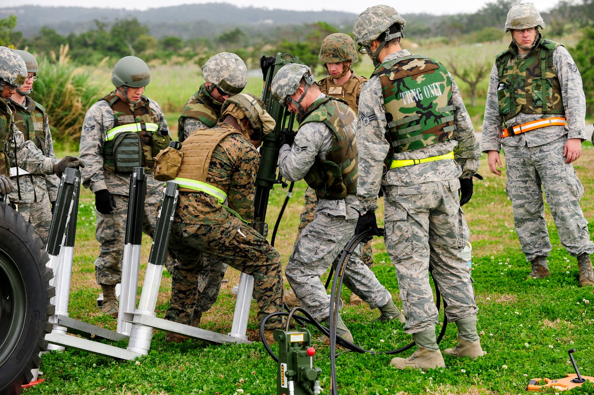 Airmen and Marines work together to plant stakes in the ground in order to establish a mobile aircraft arresting system at Kadena Air Base, Japan Feb. 26, 2015. Marines from the 172nd and 171st Engineering Companies joined 18th Civil Engineer Group Airmen in a joint airfield damage and repair contingency exercise to improve their response capabilities. (U.S. Air Force photo by Airman 1st Class John Linzmeier)