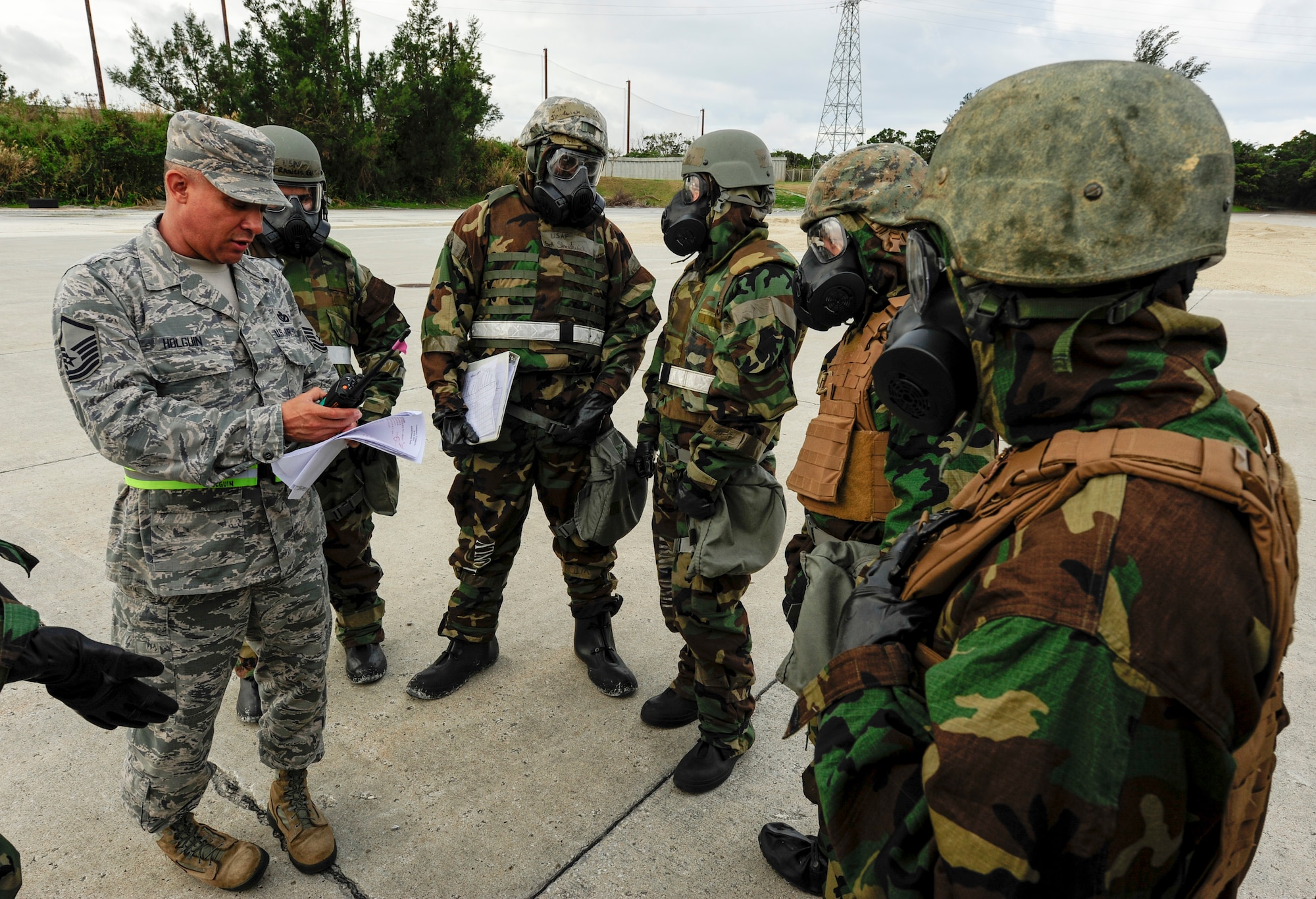 U.S. Air Force Master Sgt. Richard Holguin, 718th Civil Engineer Squadron Engineering Flight superintendent, speaks to CE Airman and Marines from the 172nd and 171st Engineering Company at Kadena Air Base, Japan Feb. 26, 2015.  Holguin acted as the wing inspection team lead and explained the differences in practice between a training exercise and a real-world scenario. Airmen and Marines donned personal protective gear in reaction to a simulated chemical attack. (U.S. Air Force photo by Airman 1st Class John Linzmeier)