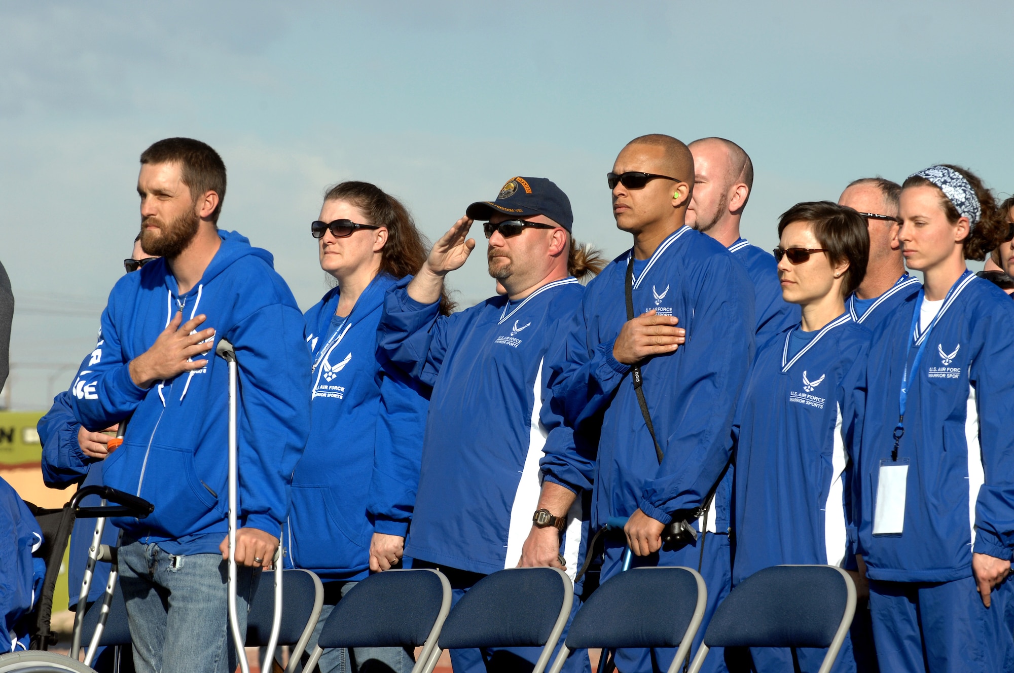 Members of the U.S. Air Force Wounded Warrior Trials Team show their respect to the flag during the opening ceremony of the 2015 Air Force Trials at Nellis Air Force Base, Nev., Feb. 27, 2015. During the trials, athletes compete in 13 various sporting events. (U.S. Air Force photo by Staff Sgt. Jack Sanders)