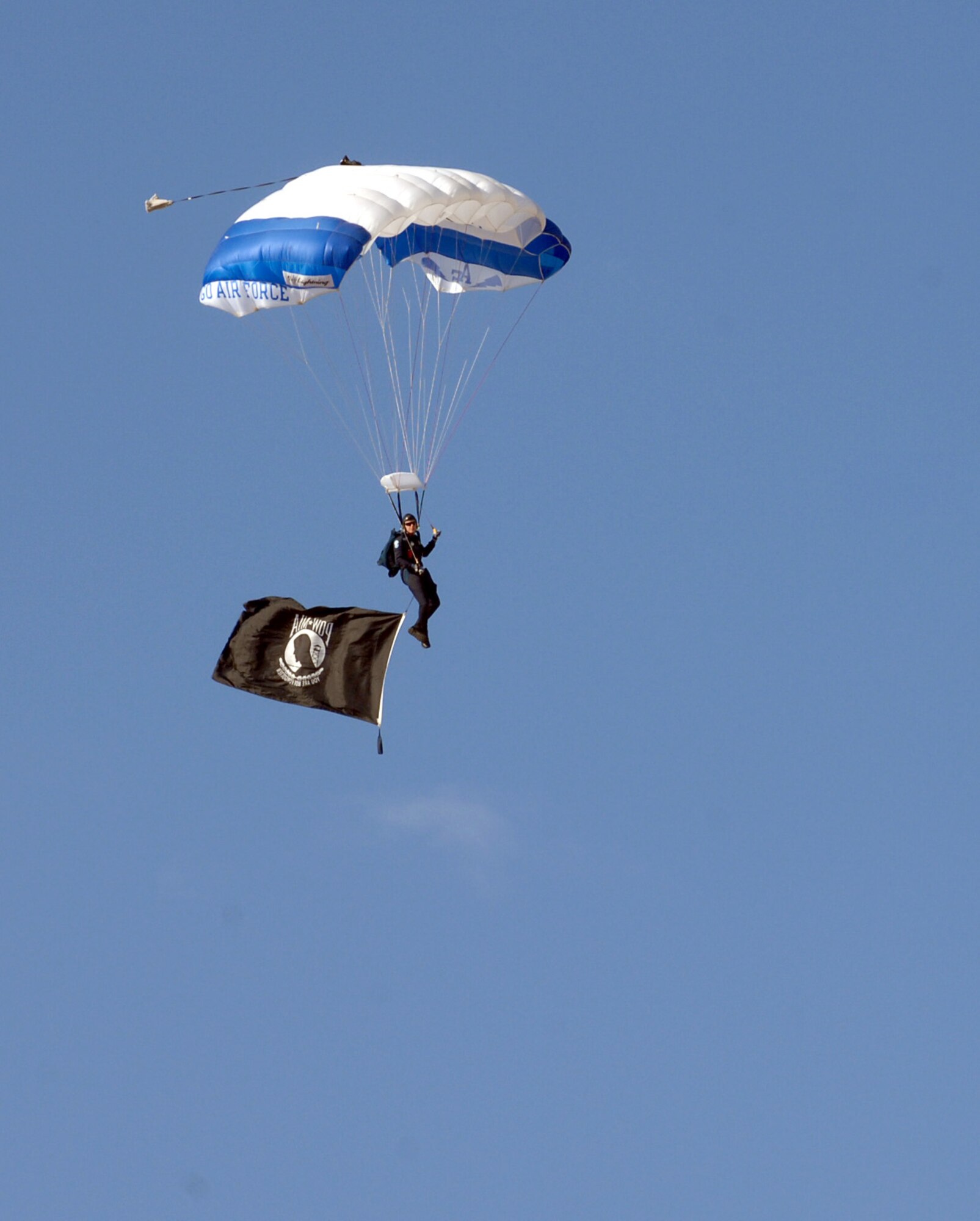 Air Force Academy Cadet Jake Sorter, Wings of Blue Parachute Team member, glides with the Prisoner of War/Missing in Action flag during the 2015 U.S. Air Force Trials opening ceremony at Nellis Air Force Base, Nev., Feb. 27, 2015. The Wings of Blue awards more than 700 Jump Wings to students who pass through the Airmanship 490 (AM-490) program at the United States Air Force Academy. (U.S. Air Force photo by Staff Sgt. Jack Sanders) 
