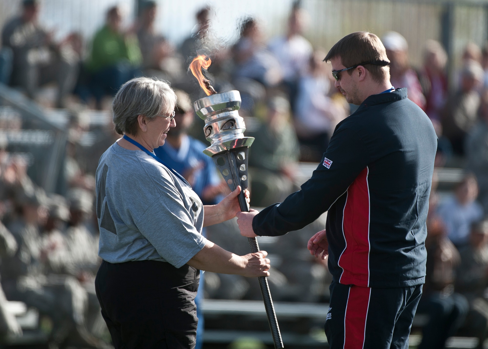 A member of the U.S. Army’s wounded warrior team accepts the ceremonial torch from a member of the British wounded warrior team during the opening ceremony of the 2015 Air Force Trials at Nellis Air Force Base, Nev., Feb. 27, 2015. The ceremonial torch was passed from the Australians, to the British, and to the U.S. Army before retired U.S. Air Force Master Sgt. Christopher Aguilera lit the trial’s cauldron. (U.S. Air Force photo by Staff Sgt. Siuta B. Ika)
