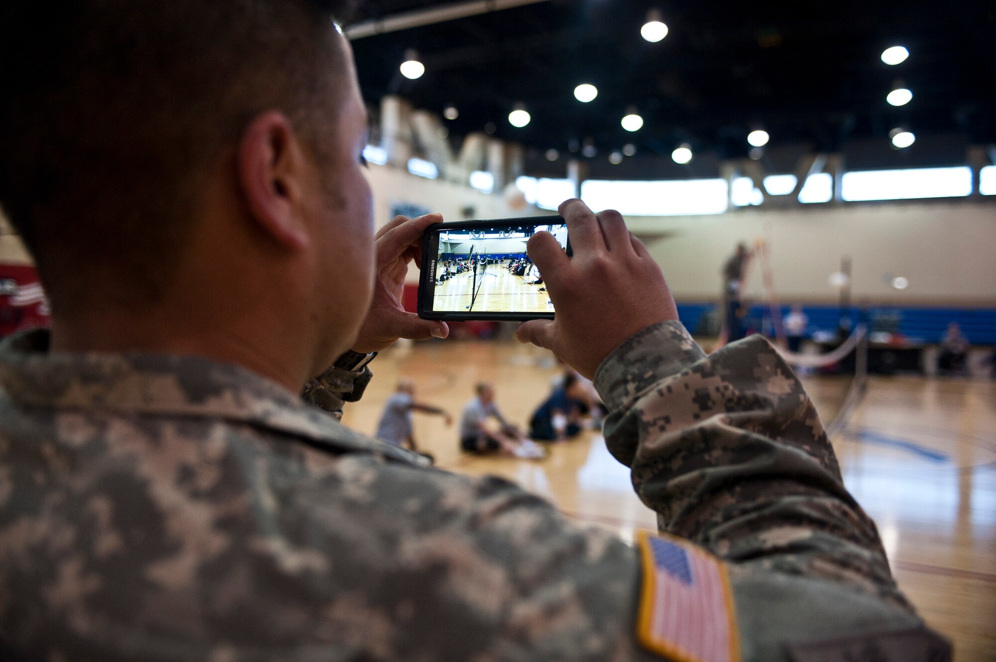 U.S. Army Staff Sgt. Edward Martinez, cadre member of the Warrior Transition Battalion, Fort Bliss, Texas, takes a picture of the U.S. Army and British sitting volleyball teams during a 2015 U.S. Air Force Trials practice session at Nellis Air Force Base, Nev., Feb. 27, 2015. More than 100 wounded, ill or injured service men and women from around the U.S., the United Kingdom and Australia will compete during the trials. (U.S. Air Force photo by Staff Sgt. Siuta B. Ika)