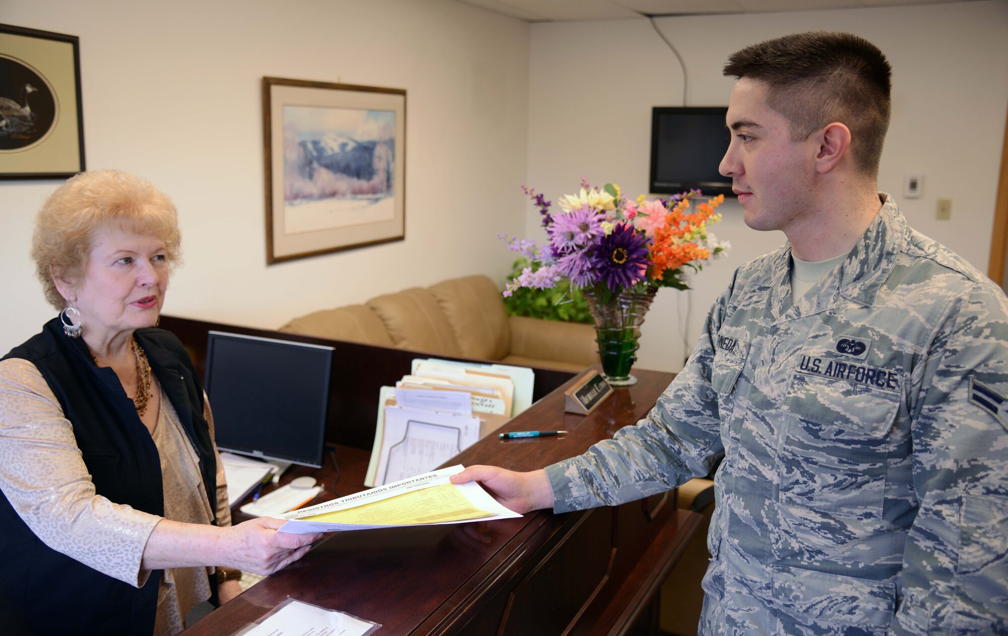 Michelle Eaton, left, 341st Missile Wing judge advocate legal assistant, hands tax paperwork to Airman 1st Class Nick Pineda, 341st MW judge advocate paralegal, March 2 at Malmstrom Air Force Base, Mont. Each individual that would like to file their taxes must fill out the proper paperwork and turn it in to the reception desk at the legal building on base. (U.S. Air Force photo/ Airman 1st Class Dillon Johnston)