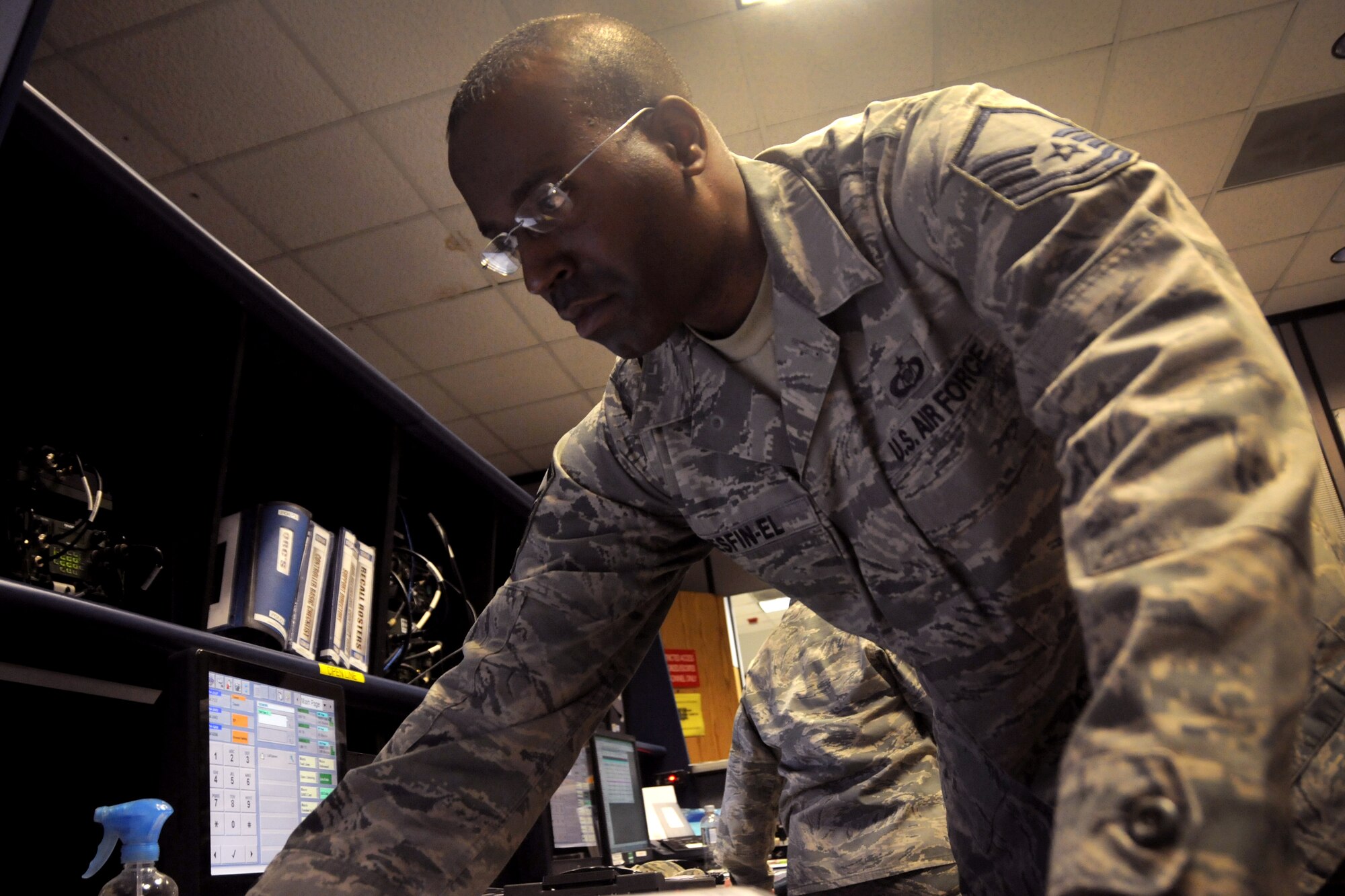Master Sgt. Elijah Mesfin-El, a 108th Wing Command Post controller, checks the console during his shift Feb. 8, 2015, at Joint Base McGuire-Dix-Lakehurst, N.J. Command post serves as the eye and ears of the wing commander. They work every day at all hours to receive and give messages for the entire wing. (U.S. Air National Guard Photo by Airman 1st Class Julia Pyun/Released)