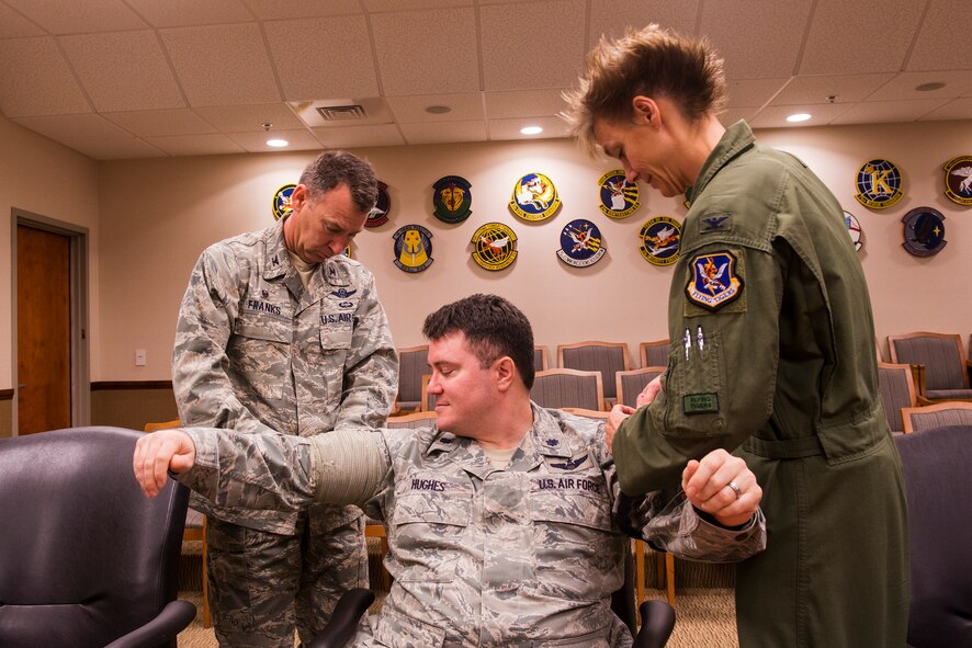 U.S. Air Force Col. Chad Franks, 23d Wing commander, left, and Col. Andra Kniep, 23d WG vice commander, right, wrap Lt. Col. Joshua Hughes, 23d WG director of staff, with a tourniquet and a bandage during a self-aid and buddy care class Feb. 25, 2015, at Moody Air Force Base, Ga. Tourniquets and bandages are two methods that are used to stop the bleedings of an open wound. (U.S. Air Force photo by Airman 1st Class Ceaira Tinsley/Released)