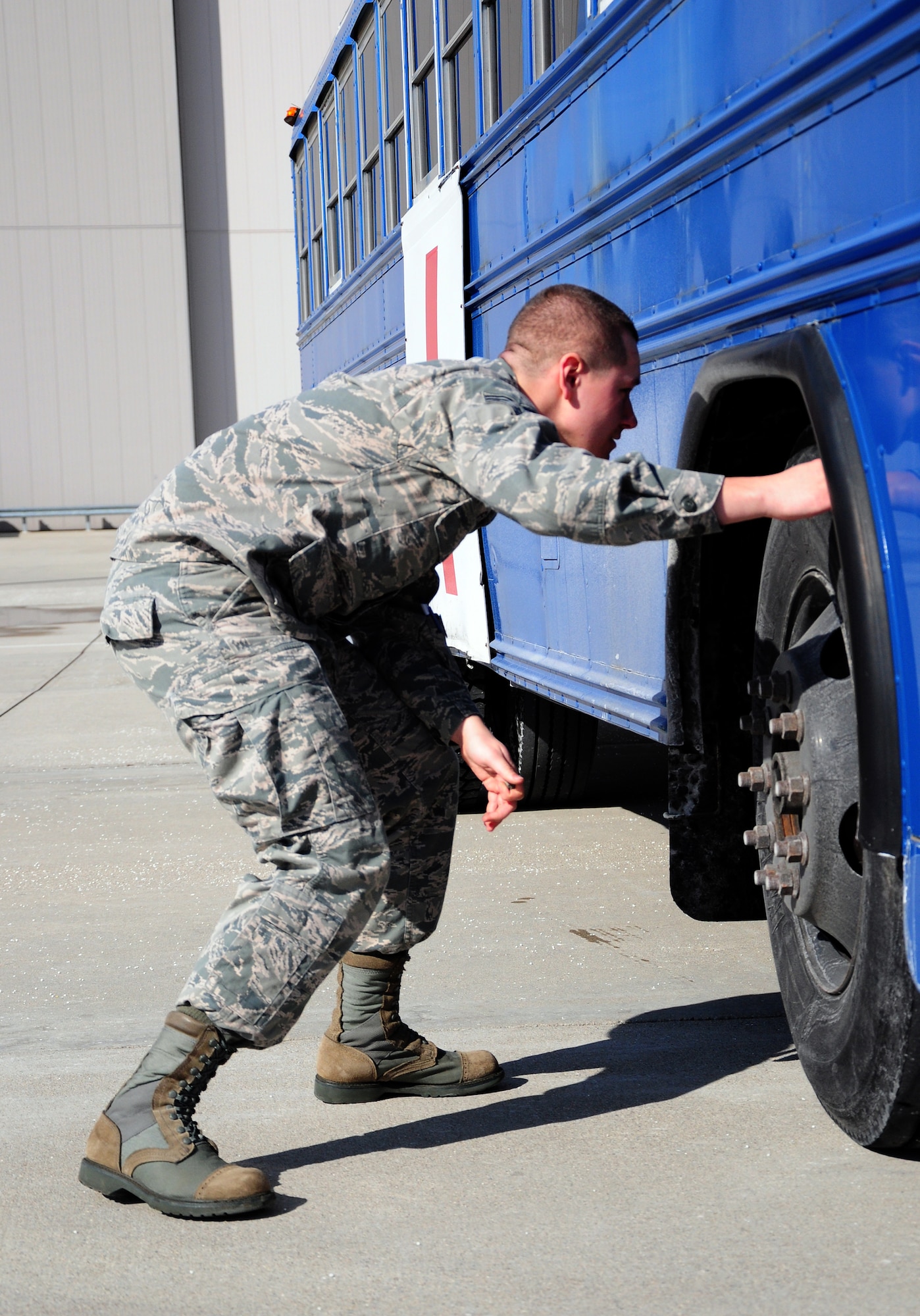 WRIGHT-PATTERSON AIR FORCE BASE, Ohio - Senior Airman Steven Flick, 445th Aeromedical Staging Squadron cardiopulomonary lab apprentice, conducts a foreign object debris check on an ambulance bus during an airfield driving course Feb. 7, 2015. The course better prepares ASTS personnel on how to transport patients to and from an aircraft on the flightline using an Ambus. (U.S. Air Force photo/Tech. Sgt. Patrick O'Reilly)