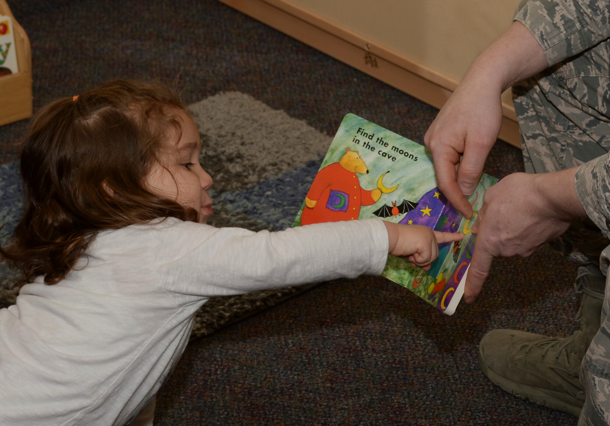 A child points to a book held by U.S. Air Force Col. Joe McFall, 52nd Fighter Wing commander, during a Read Across America event at a child development center at Spangdahlem Air Base, Germany, March 2, 2015. McFall and other leaders from the 52nd FW will read to children as part of the annual nationwide observance highlighting literacy among children. (U.S. Air Force photo by Staff Sgt. Joe W. McFadden/Released)