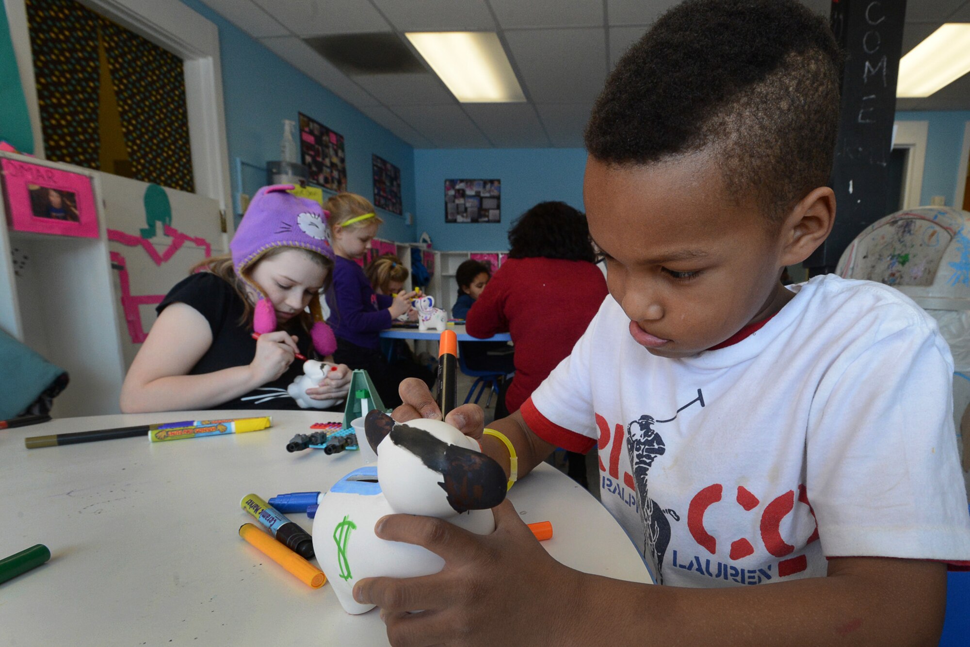 Jerod (PJ) Prather decorates an elephant ‘piggy bank’ as part of a Military Saves Week event at the School Age Program Feb. 25. The program, sponsored by Hanscom Federal Credit Union and hosted by the Airmen and Family Readiness Center and School Age Program, was designed to teach children the many ways to earn money, save the money they earn and responsibly spend it. (U.S. Air Force photo by Jerry Saslav)