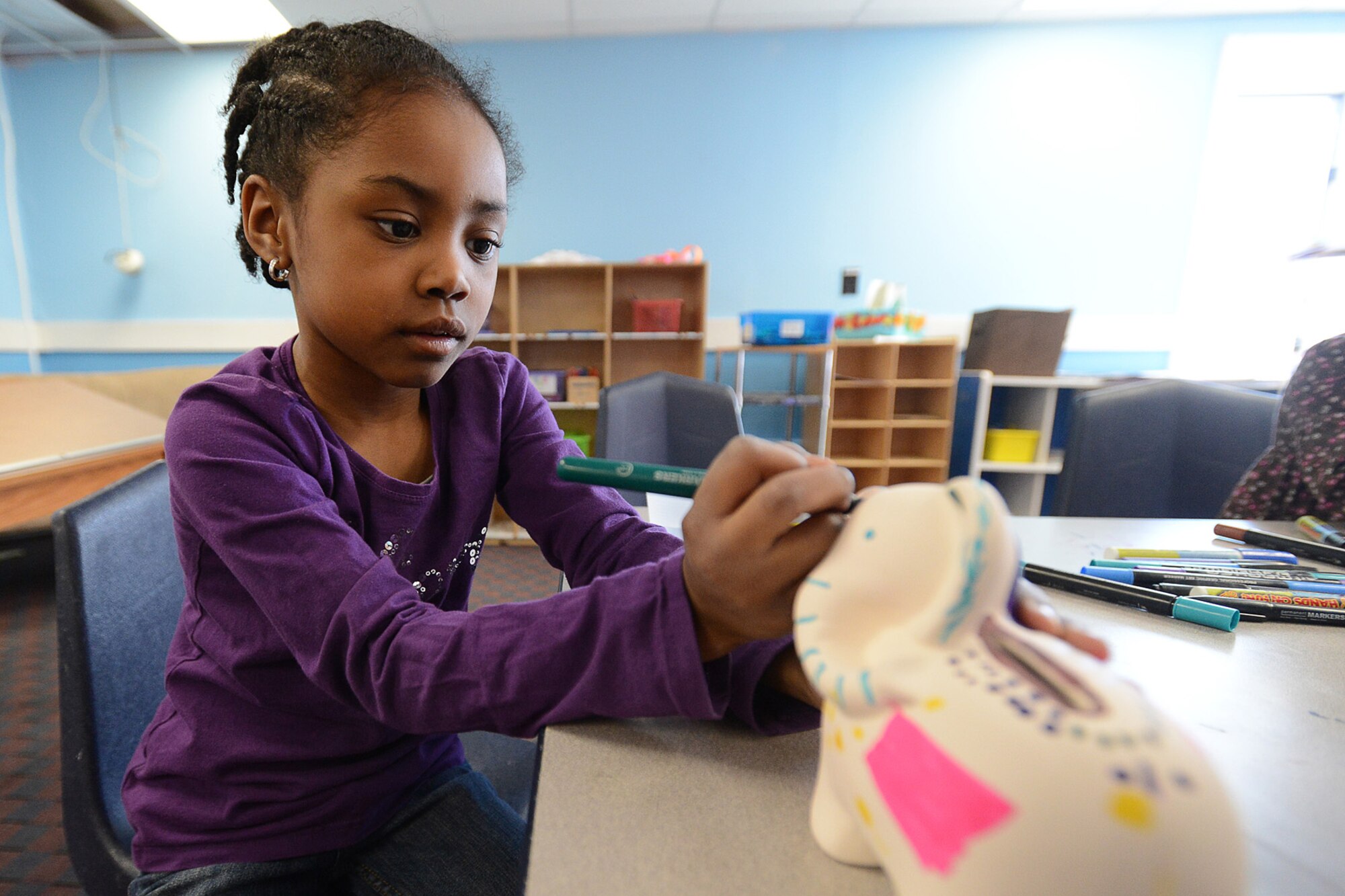 Justice Davis decorates an elephant ‘piggy bank’ as part of a Military Saves Week event at the School Age Program Feb. 25. To encourage and help service members save more successfully, the Airman and Family Readiness Center hosted several events throughout the week to offer military families and Defense Department civilians services and information on money management, goal setting, credit scores and more. (U.S. Air Force photo by Jerry Saslav)