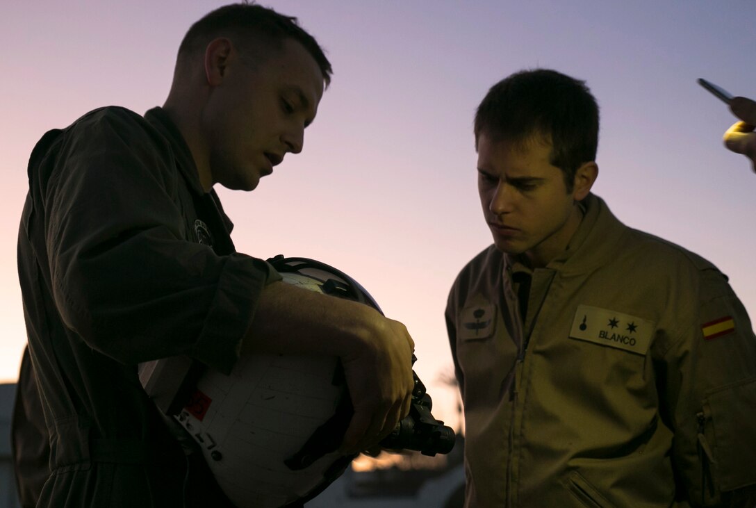 U.S. Marine Corps Capt. Shawn Stelzel, left, a pilot with Special-Purpose Marine Air-Ground Task Force Crisis Response-Africa, demonstrates how to attach a night vision devise to an American aviator’s helmet prior to flying with Spanish pilots at an airfield near Morón Air Base, Spain, Feb. 24, 2015. A Spanish pilot flew with Stelzel inside a Marine MV-22B as it completed a series of night landing drills with a Spanish helicopter. (U.S. Marine Corps photo by Sgt. Paul Peterson/Released)
