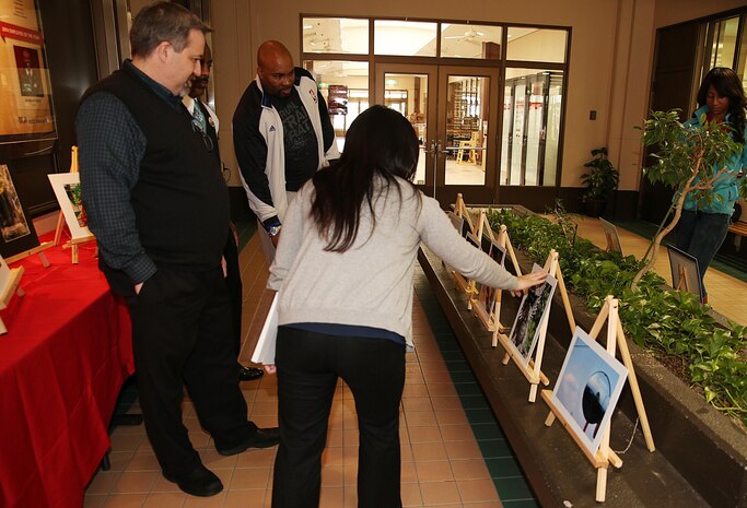 Judges of the 2015 Youth & Teen Center Imagemakers Photography Exhibit, critique contestants artwork at the Crossroads Mall aboard Marine Corps Air Station Iwakuni, Japan, Feb. 25, 2015. Sponsored by Sony Corporation, winners of this local contest will receive a merit certificate for their participation and move forward to the overseas region competition held in Singapore. Contestants may then compete against photographers from the five different U.S. regions for the national championship prize; a free, all expense-paid trip to San Diego, Calif., to visit the San Diego Sony Plant.