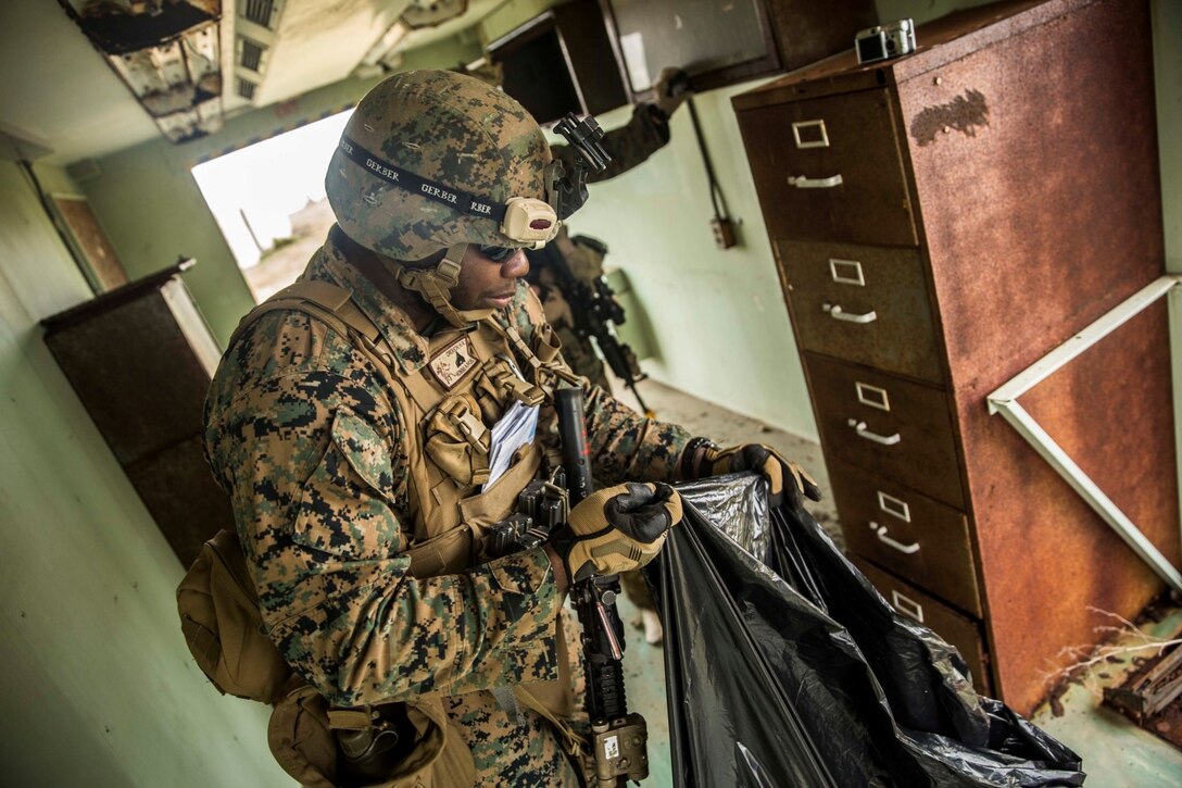 U.S. Marine Cpl. Heath Crouch gathers intelligence  during a mechanized raid as part of Amphibious Squadron/Marine Expeditionary Unit Integration Training (PMINT) aboard San Clemente Island, Calif., March 1, 2015. Crouch is an intelligence analyst with Kilo Company, Battalion Landing Team 3rd Battalion, 1st Marine Regiment, 15th Marine Expeditionary Unit. During the training, Marines rehearsed intelligence gathering and crime scene documentation. (U.S. Marine Corps photo by Sgt. Emmanuel Ramos/Released)