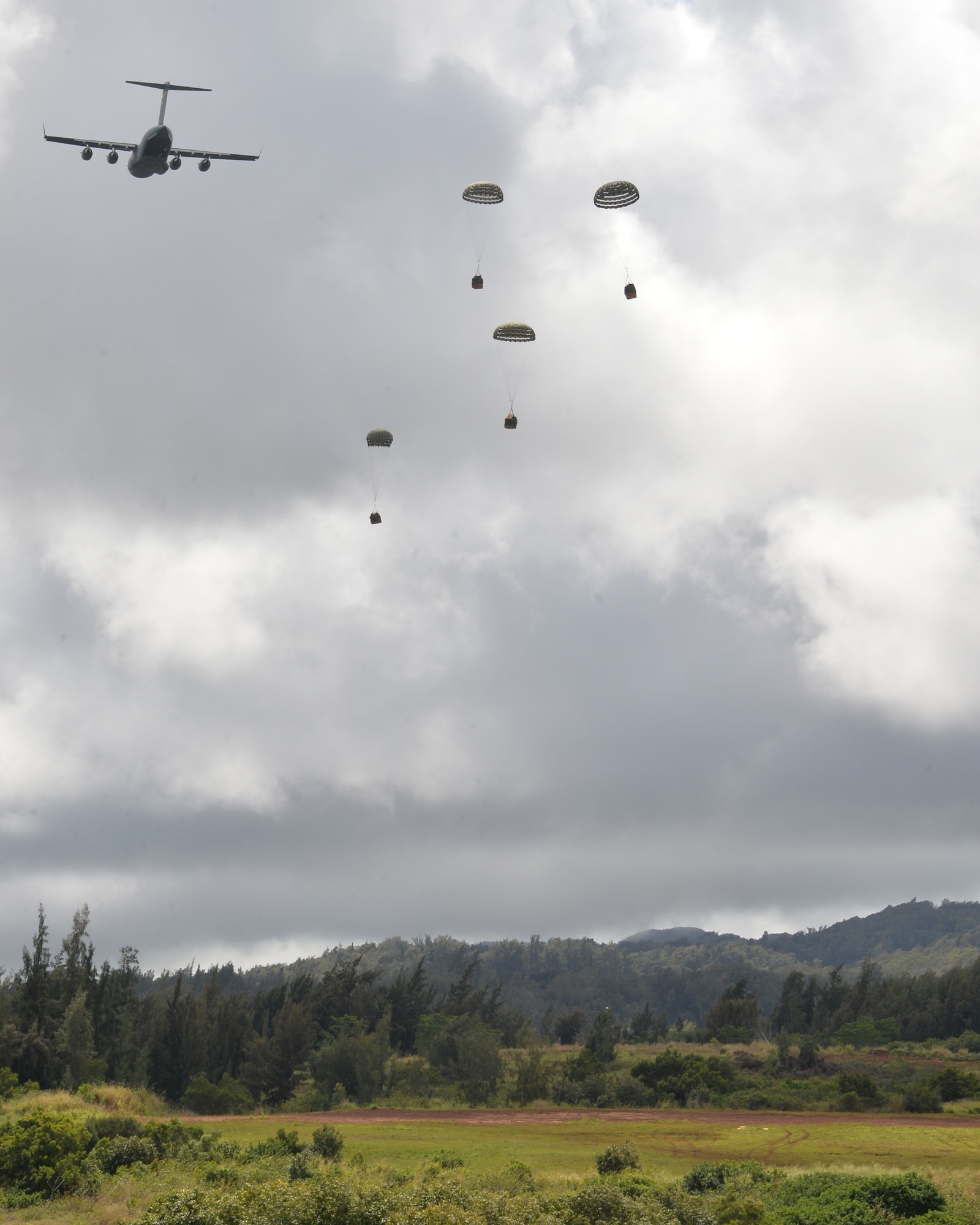 A C-17 Globalmaster III, from the 535th Air Lift Squadron at Joint Base Pearl Harbor-Hickam, Hawaii, completes an air drop of four combat delivery systems on Kahuku Training Area, Hawaii, March 2, 2015. The air drop will resupply the Army’s 25th Infantry Division during exercise Lightning Forge. Each combat delivery system has a 26 foot, high velocity parachute attached which opens as it exits the aircraft. (U.S. Air Force photo by Tech. Sgt. Aaron Oelrich/Released)