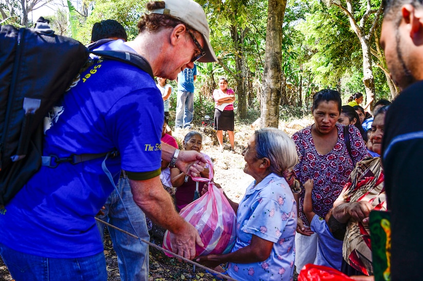 U.S. Ambassador to the Republic of Honduras, James Nealon, passes his bag of donated food and supplies to a villager in Laguna, Honduras, Feb. 28, 2015. As part of the 59th Chapel Hike, more than 172 members assigned to Joint Task Force-Bravo laced up their hiking boots and completed a seven-mile round trip hike to deliver over 4,500-pounds of donated try goods to villagers in need. (U.S. Air Force photo/Tech. Sgt. Heather Redman) 